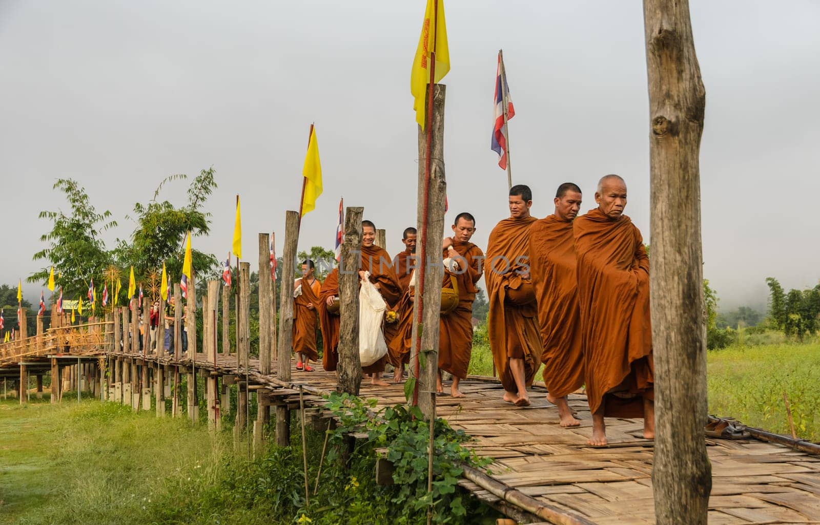 MAE HONG SON, THAILAND - NOVEMBER 21, 2015: Morning Buddhist Almsgiving at Zu Tong Pae bamboo bridge in Mae Hong Son, Thailand. Monks go on a daily almsround to collect food.