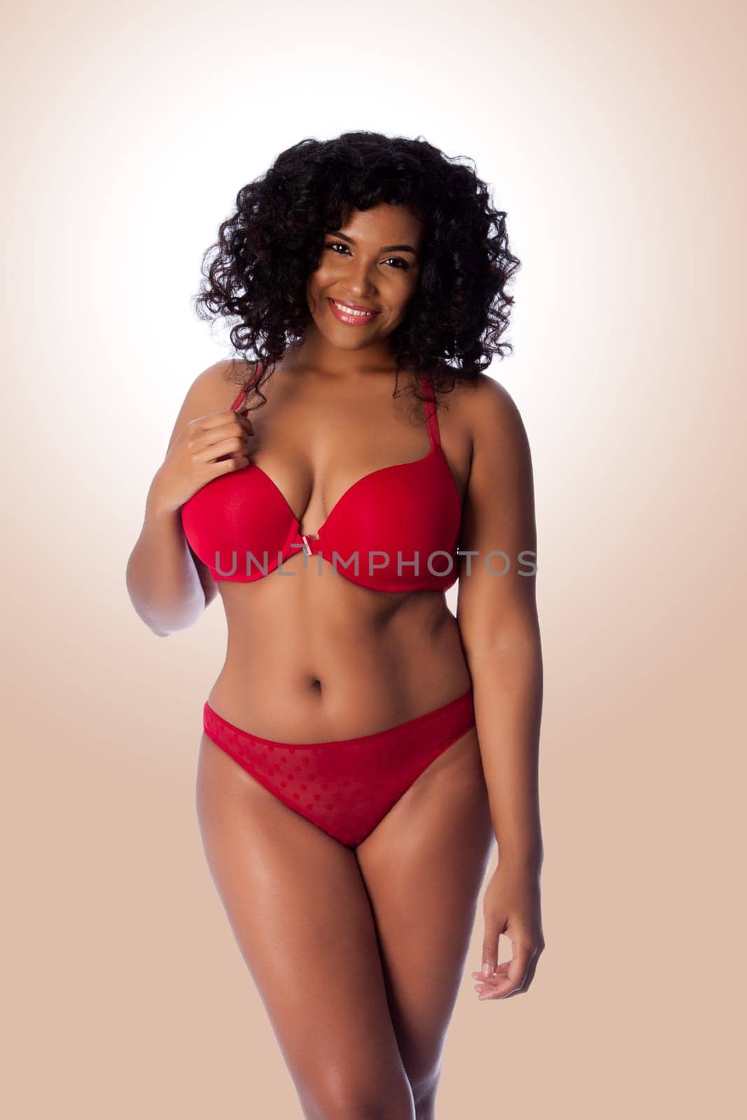 Beautiful happy plus size sexy woman with curly hair in red lingerie bra and thong underwear.