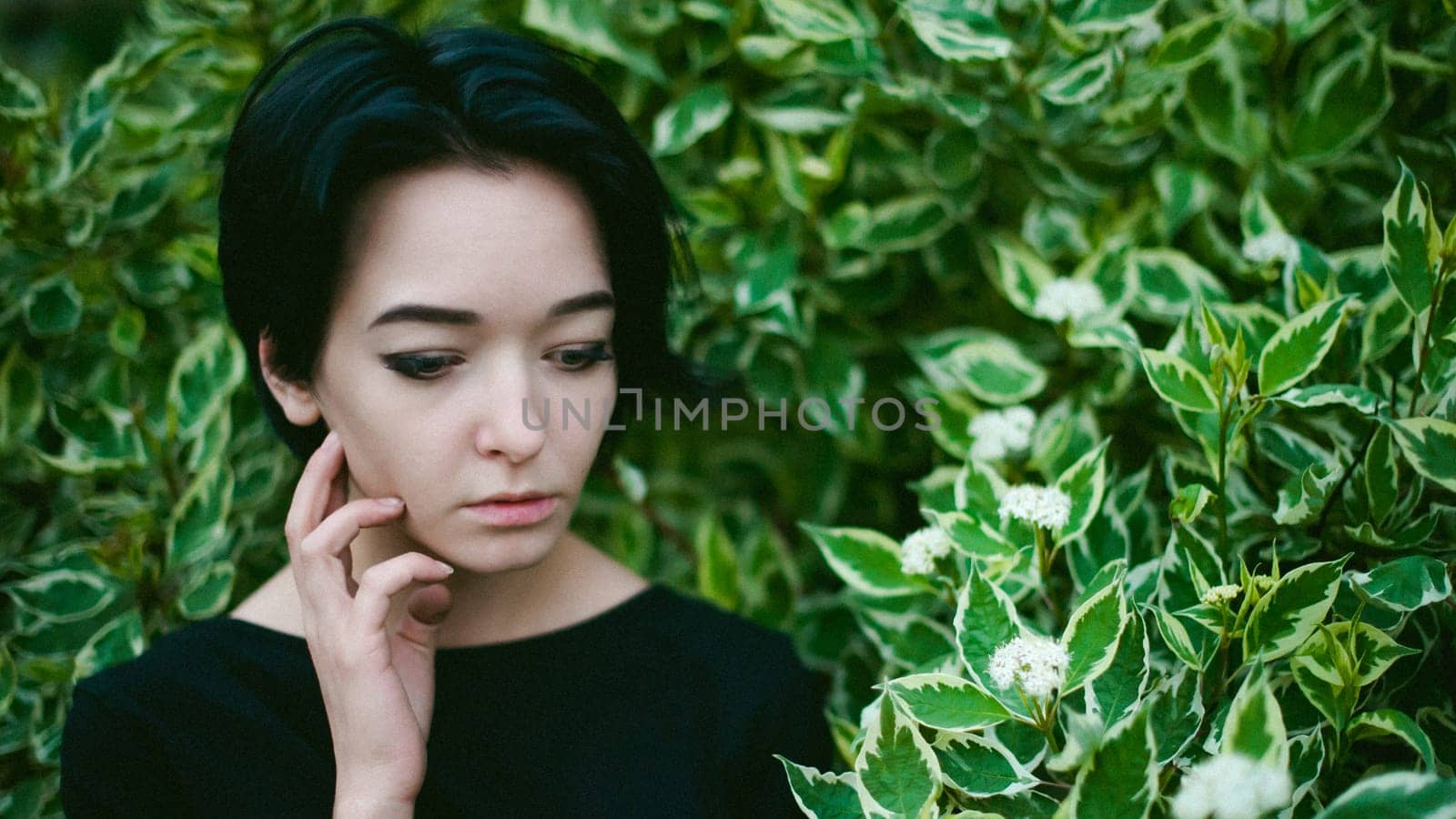 young woman with beautiful feet dressed in black dress, against a backdrop of urban landscapes bush. Street fashion.