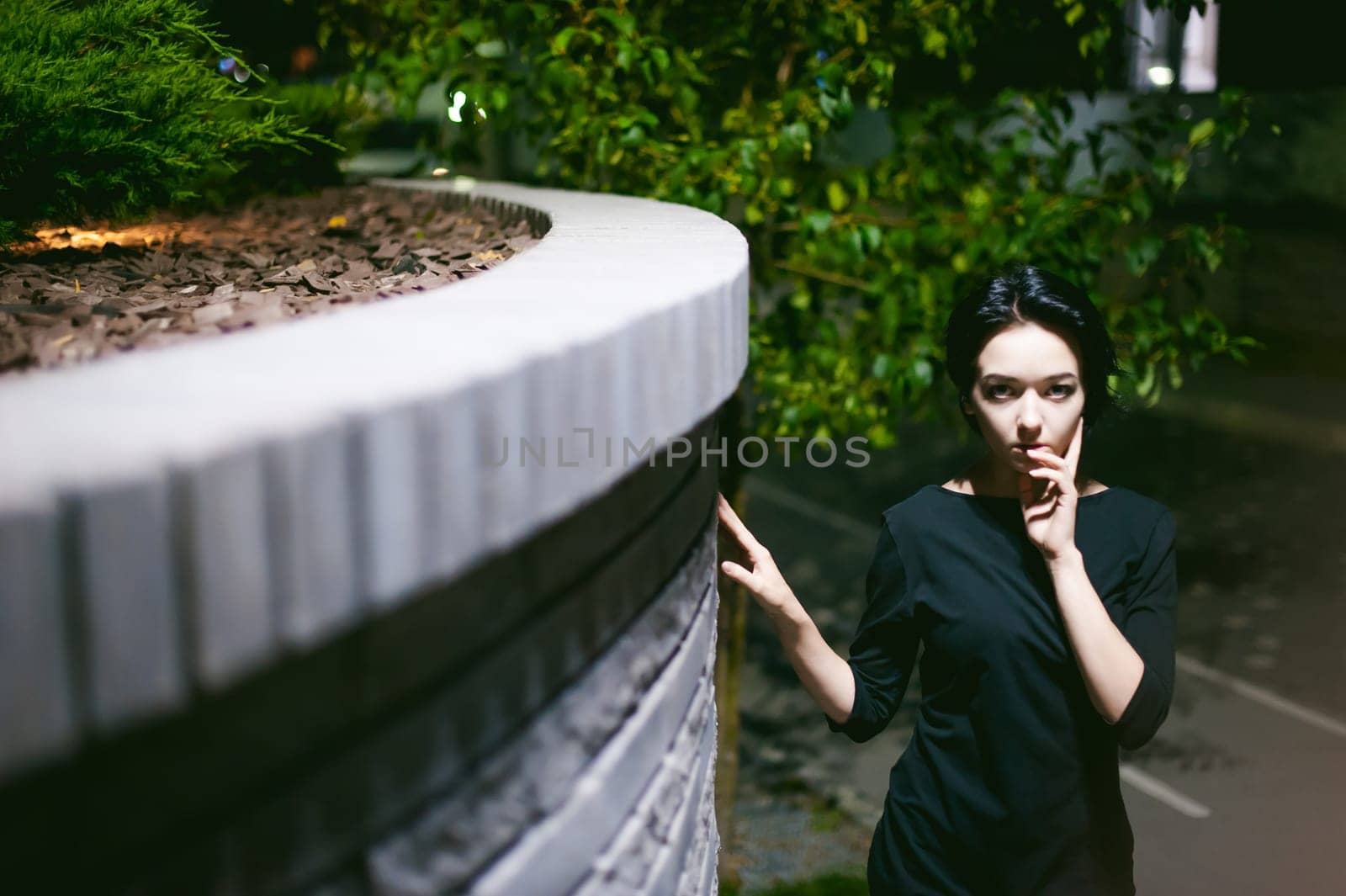young woman with beautiful feet dressed in white sneakers and black dress, against a backdrop of urban landscapes. Street fashion. night dark style
