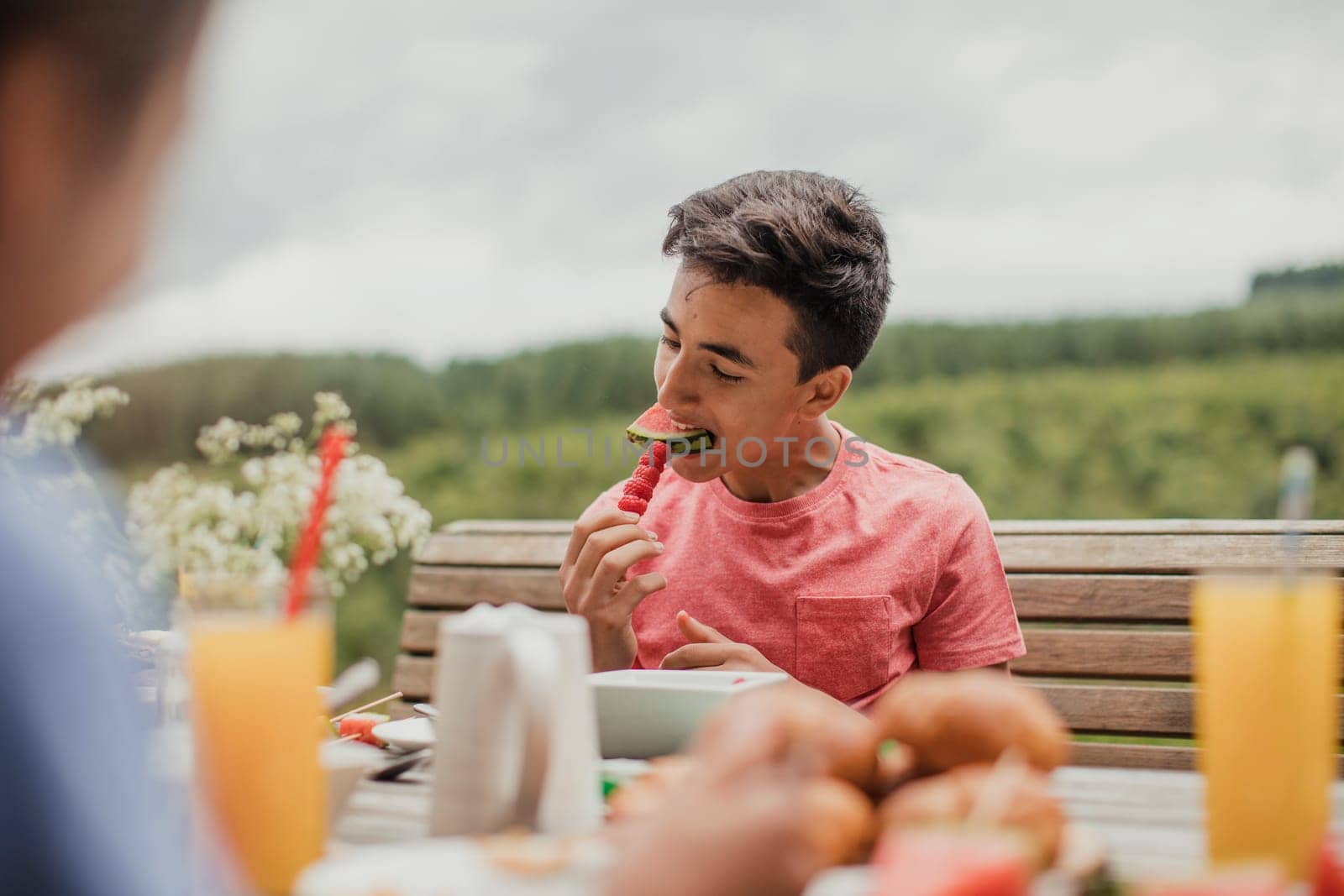 Teenage boy sitting outside and eating fruit.