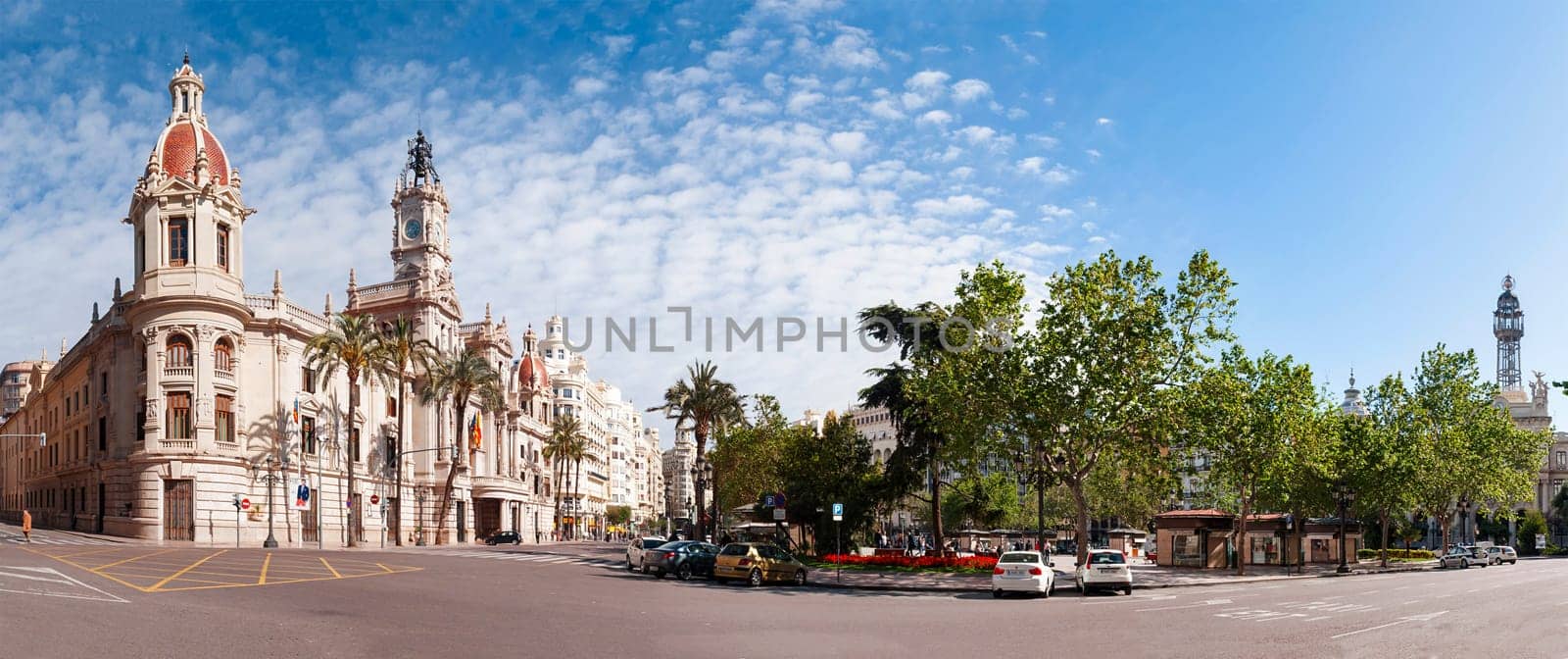 Valencia, Spain, May 1st, 2013: Town square (Plaza del Ayuntamiento) with palm trees and parked cars on a sunny day in Valencia, Spain