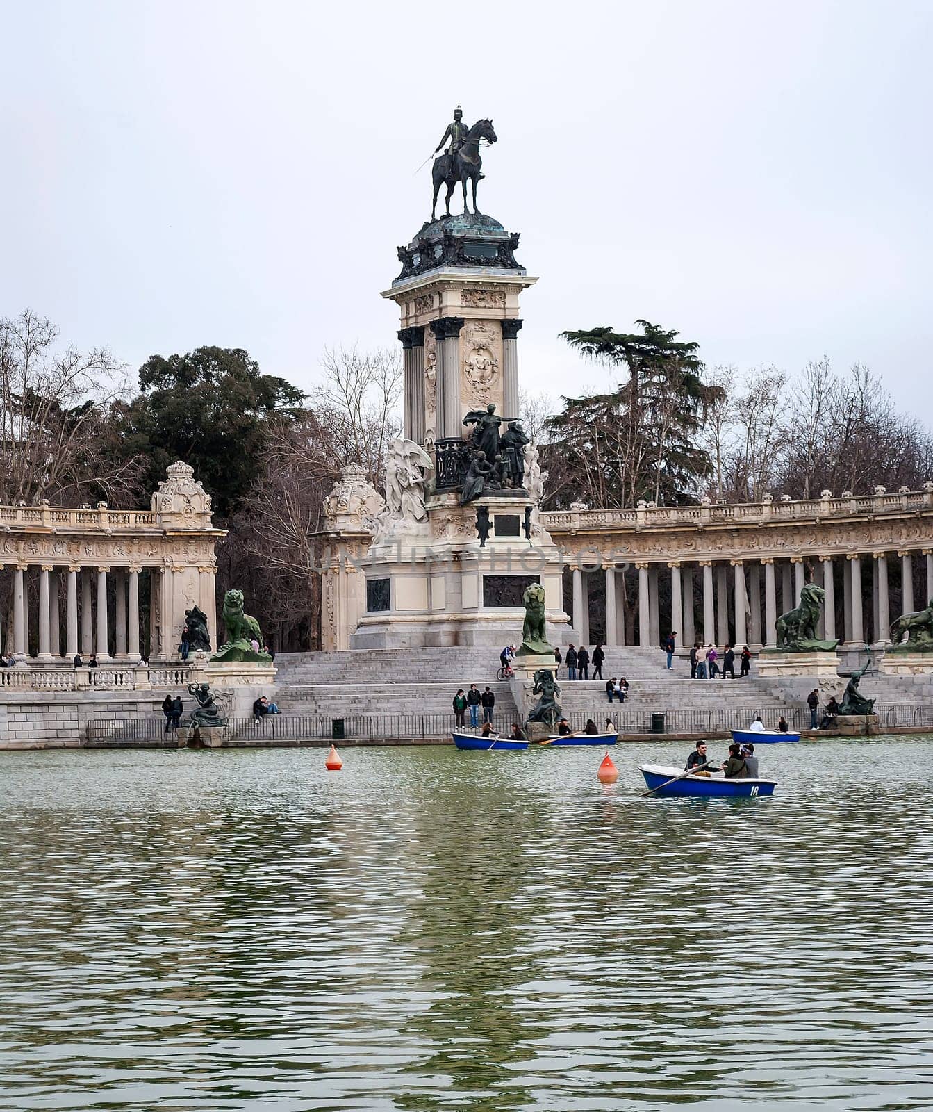 Madrid, Spain, February 2010: Equestrian monument to Alfonso XII with the lake and the tourists on the boats inside the Parque del Buen Retiro