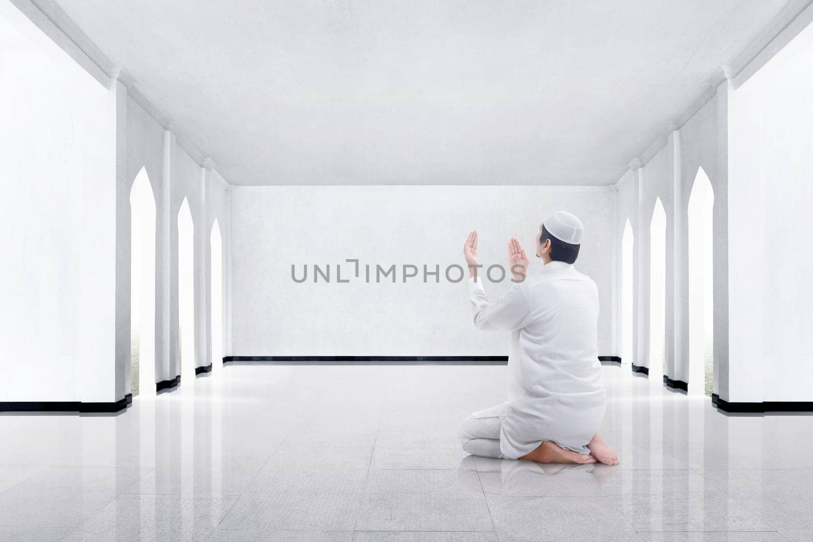 Back view of asian muslim man kneeling and praying to god in the mosque