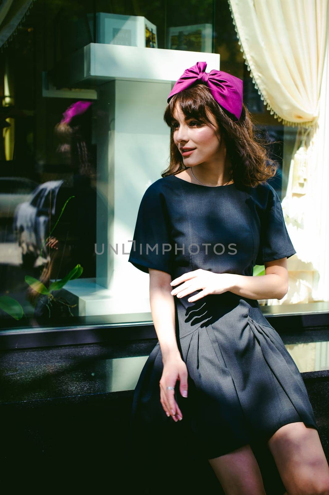 Beautiful woman in a dark stylish dress strolls along the street, near boutiques. Portrait of a fashionable girl