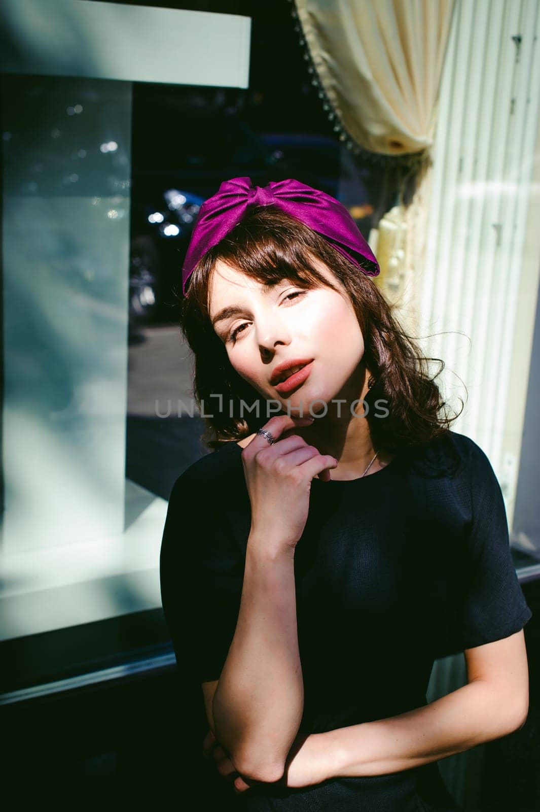 Beautiful woman in a dark stylish dress strolls along the street, near boutiques. Portrait of a fashionable girl