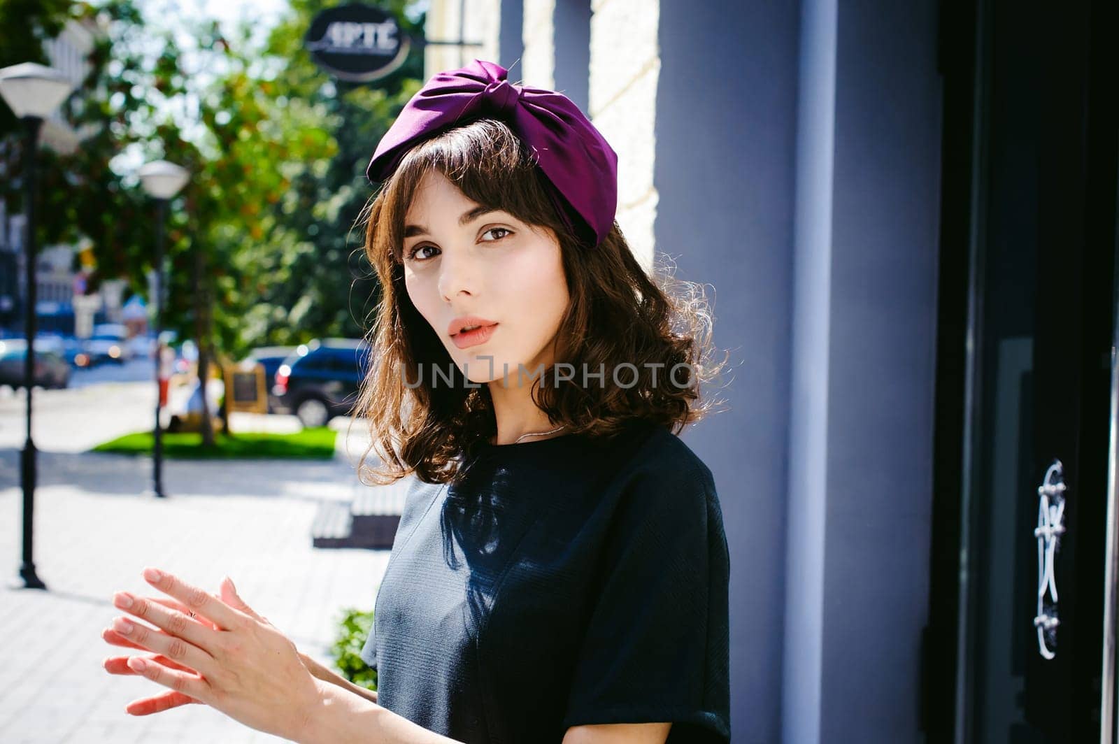 Beautiful woman in a dark stylish dress strolls along the street, near boutiques. Portrait of a fashionable girl