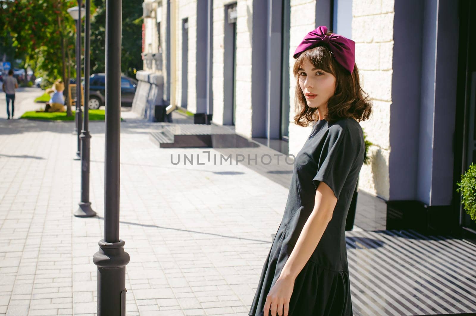 Beautiful woman in a dark stylish dress strolls along the street, near boutiques. Portrait of a fashionable girl