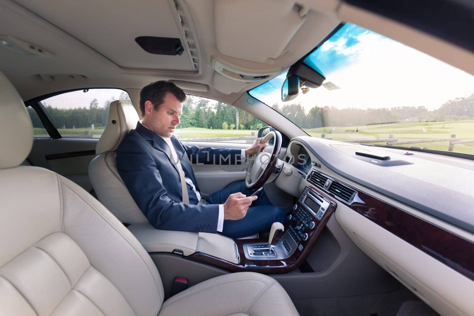 Businessman using cell phone and texting while driving not paying attention to the road.
