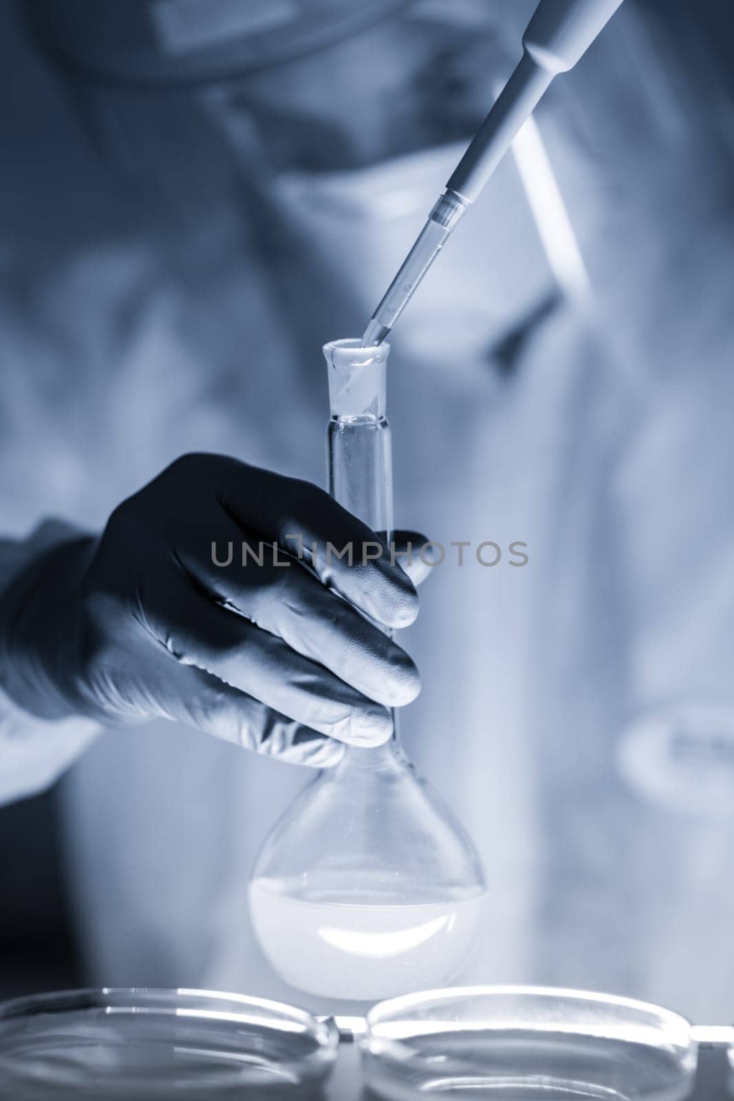 Life scientist researching in laboratory. Focused life science professional pipetting human serum media containing HIV infected cells. High protection degree work. Healthcare and biotechnology.