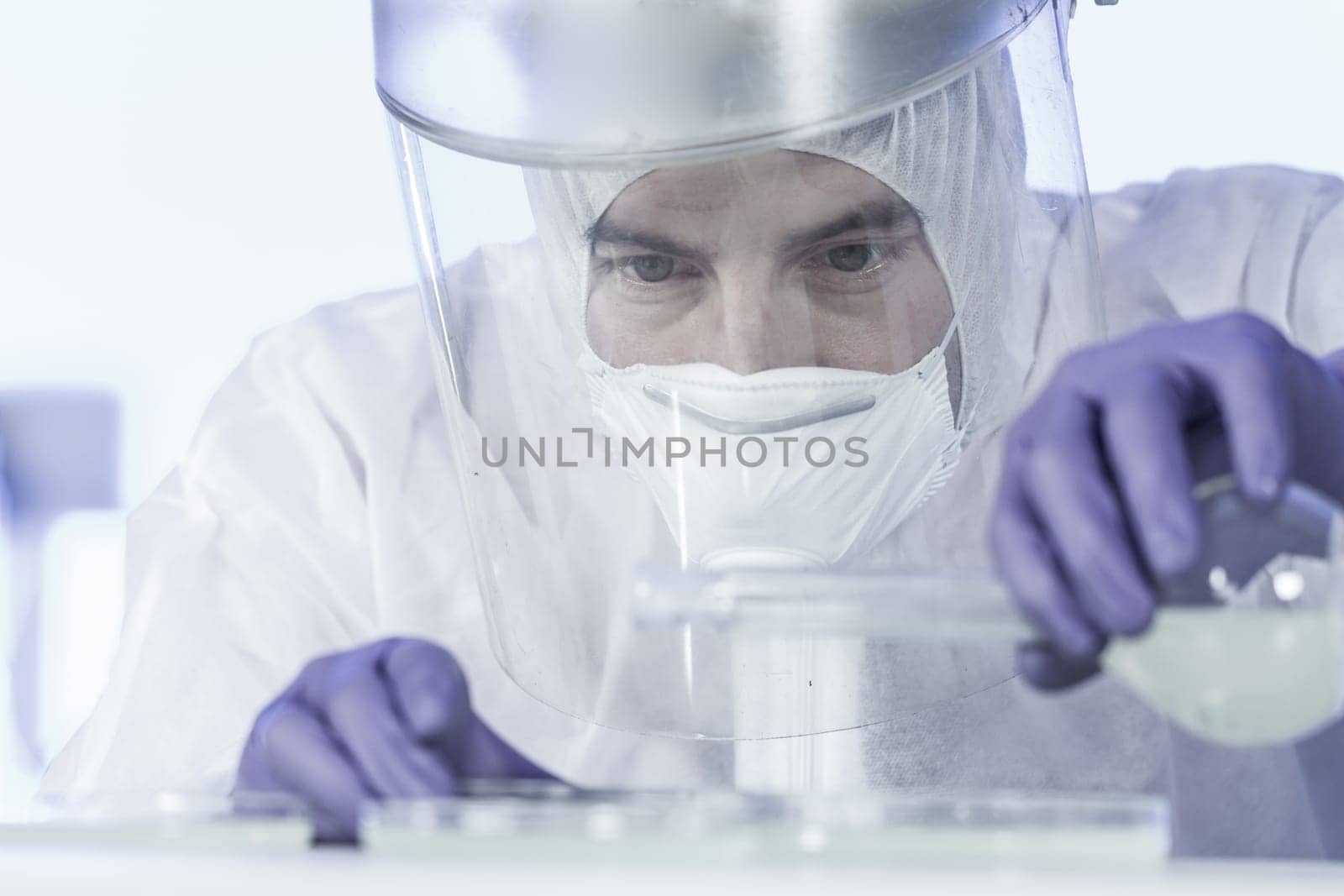 Life scientist researching in bio hazard laboratory. Focused life science professional working on experiment in high protection degree work laboratory. Healthcare and biotechnology.