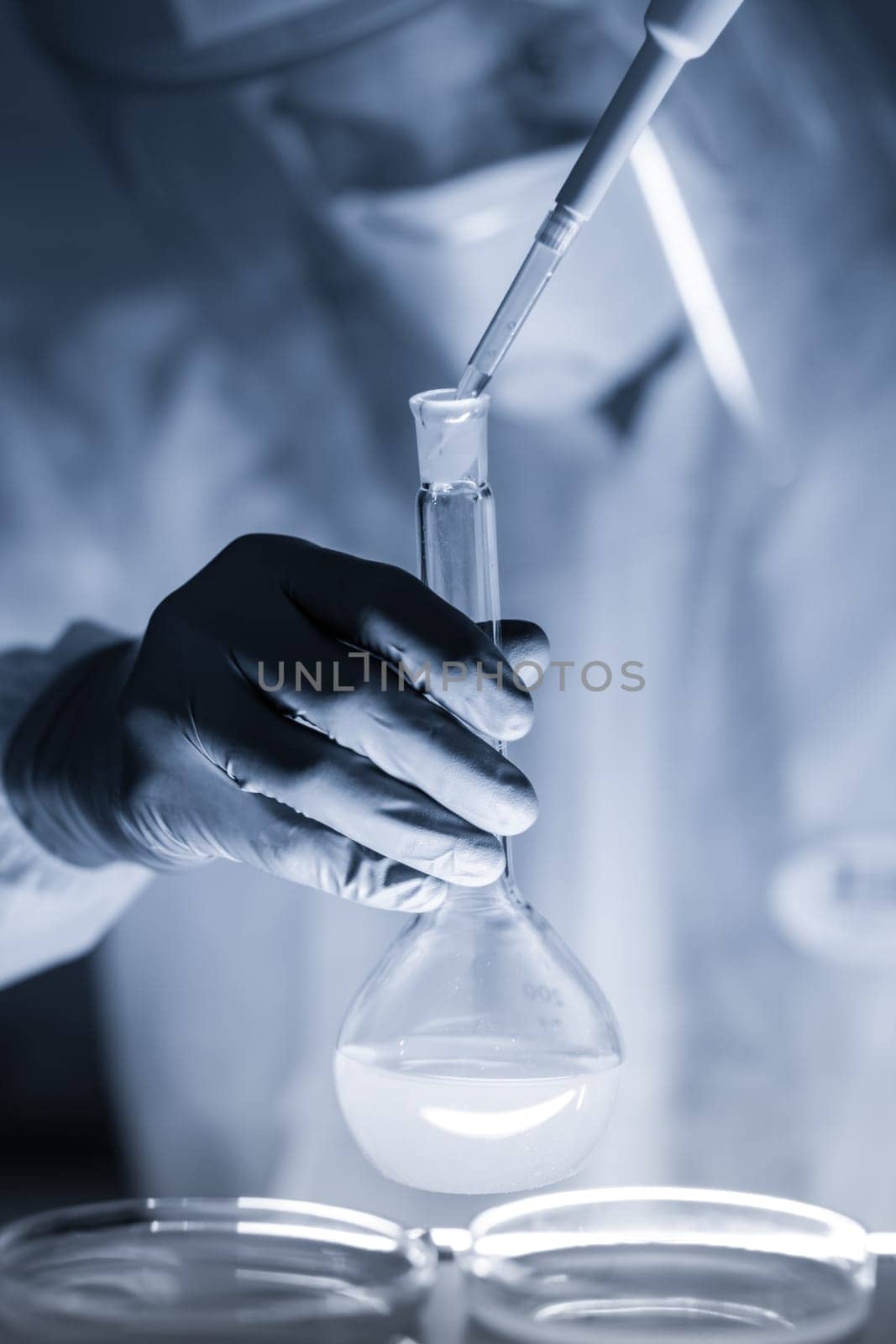 Life scientist researching in laboratory. Focused life science professional pipetting human serum media containing HIV infected cells. High protection degree work. Healthcare and biotechnology.