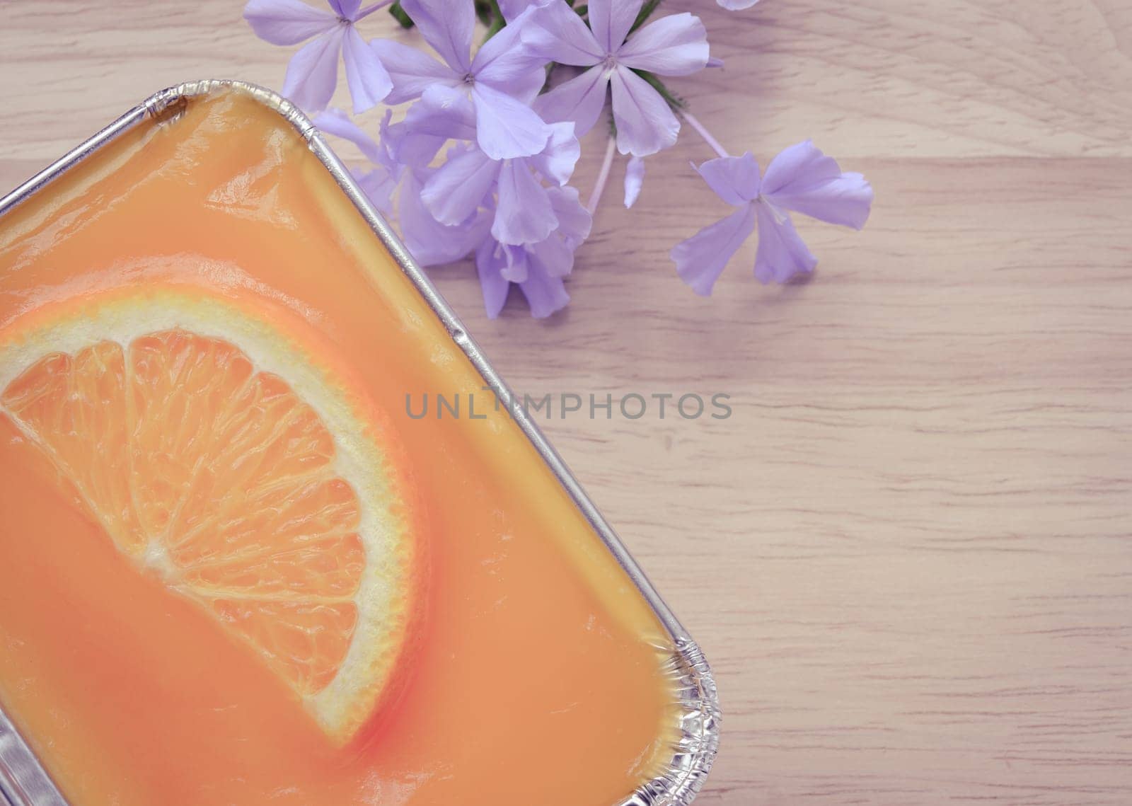 Orange soft cake with sliced orange fruit in aluminum foil tray on wooden background. Retro-Vintage filter effect