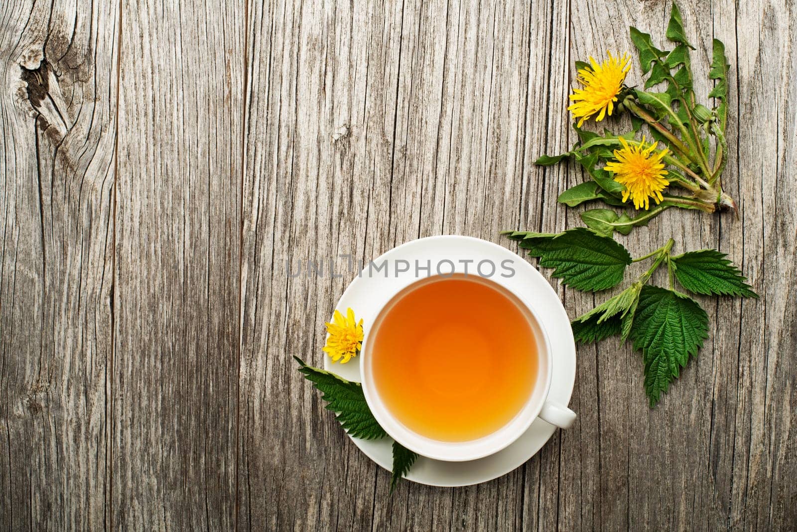 Cup of healthy herbal tea with dandelion and nettle on wooden background. Herbal medicine