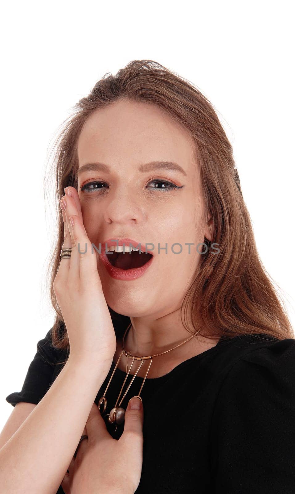 A close up image of a young woman telling a secret behind her hand,.in a black dress and necklace, isolate for white background.