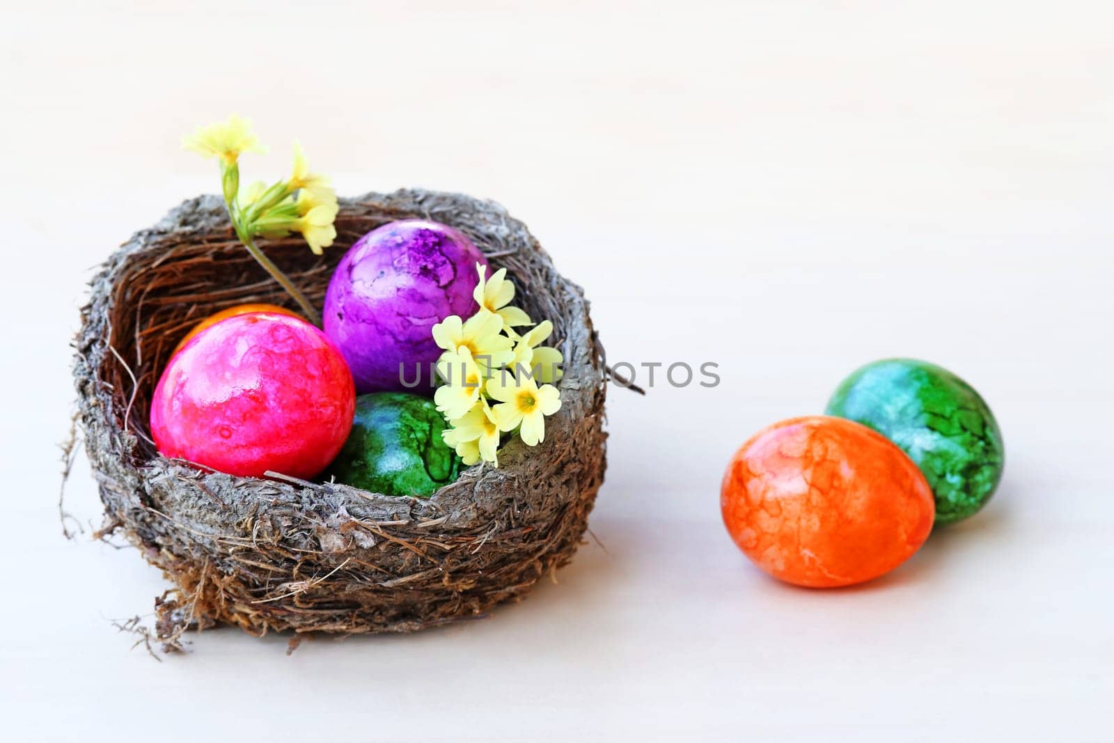An Easter nest with colorful Easter eggs on a light wooden background