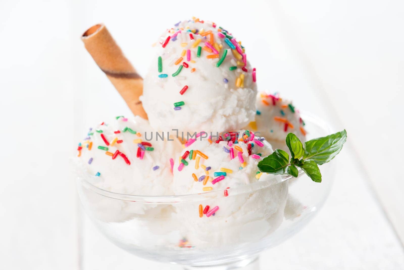 Milk ice cream in cup with waffle on white rustic wooden background.