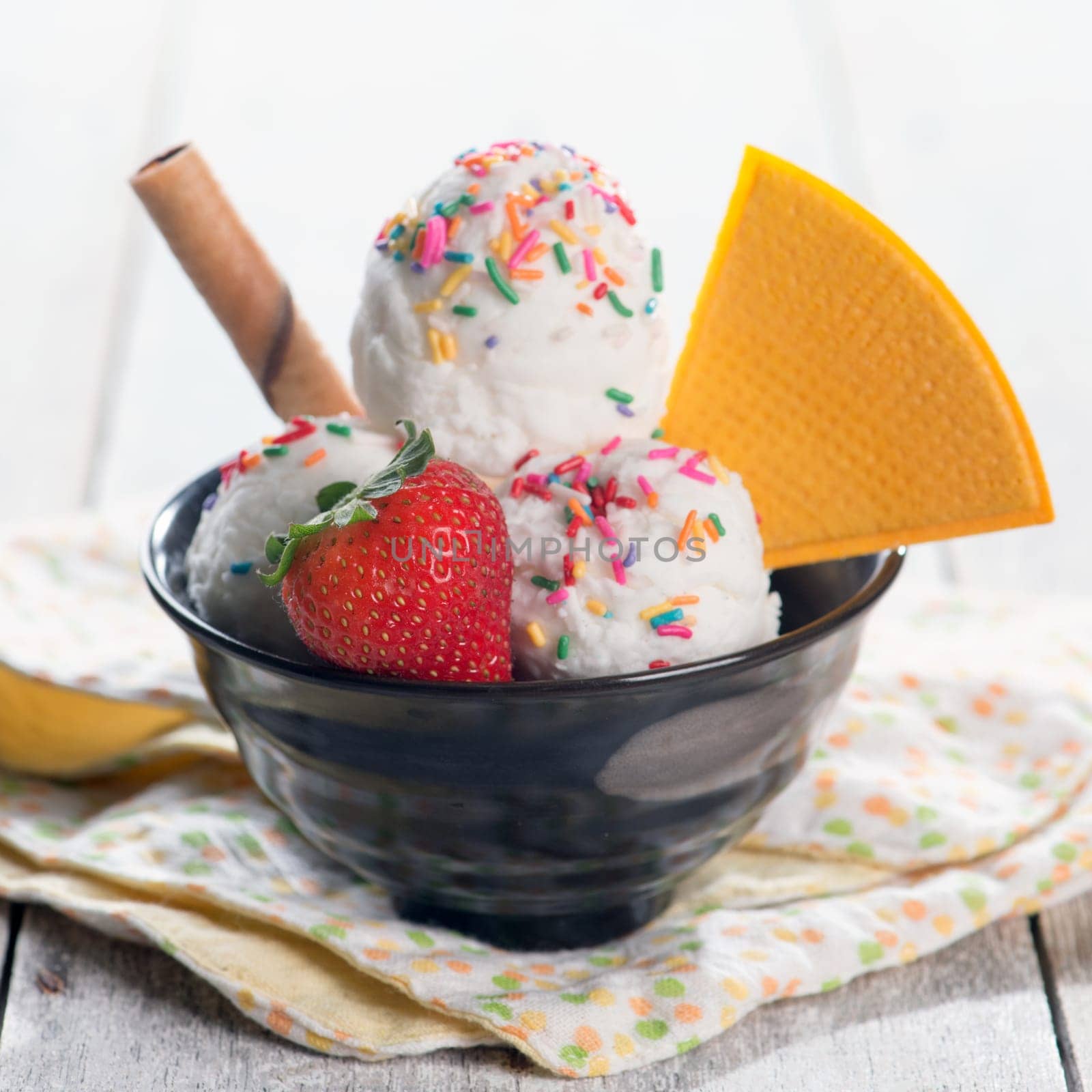 Milk ice cream in bowl with waffle on white rustic wooden background.