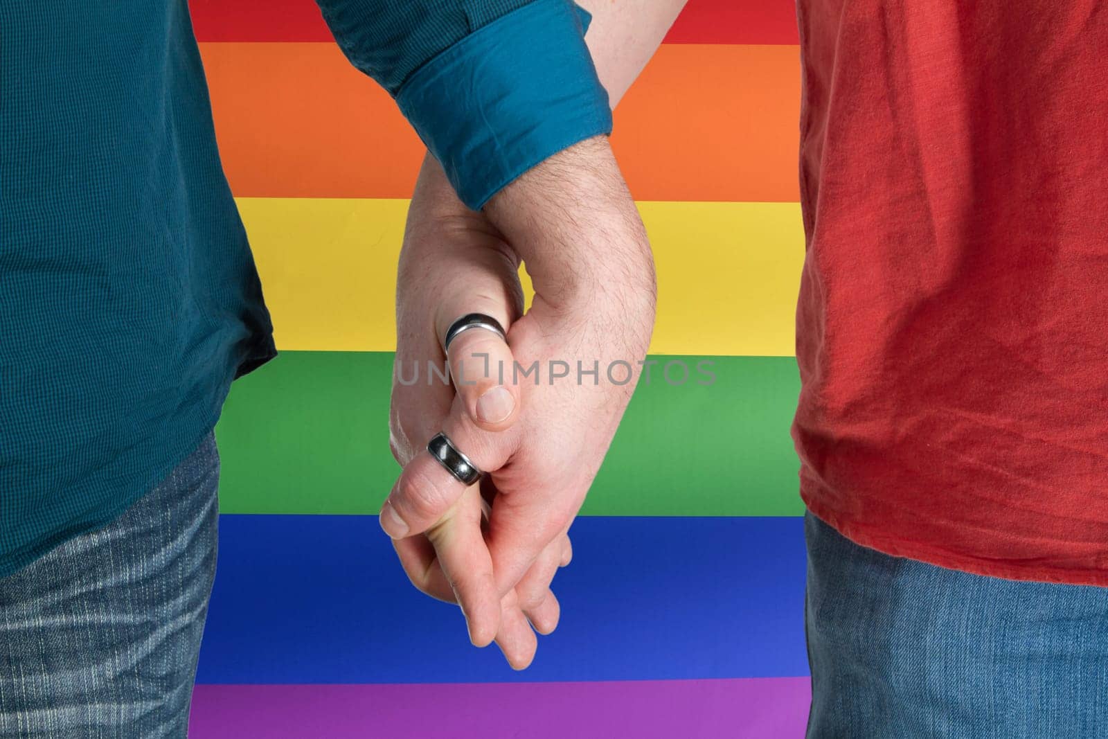 Men's hands with ring on rainbow flag as background