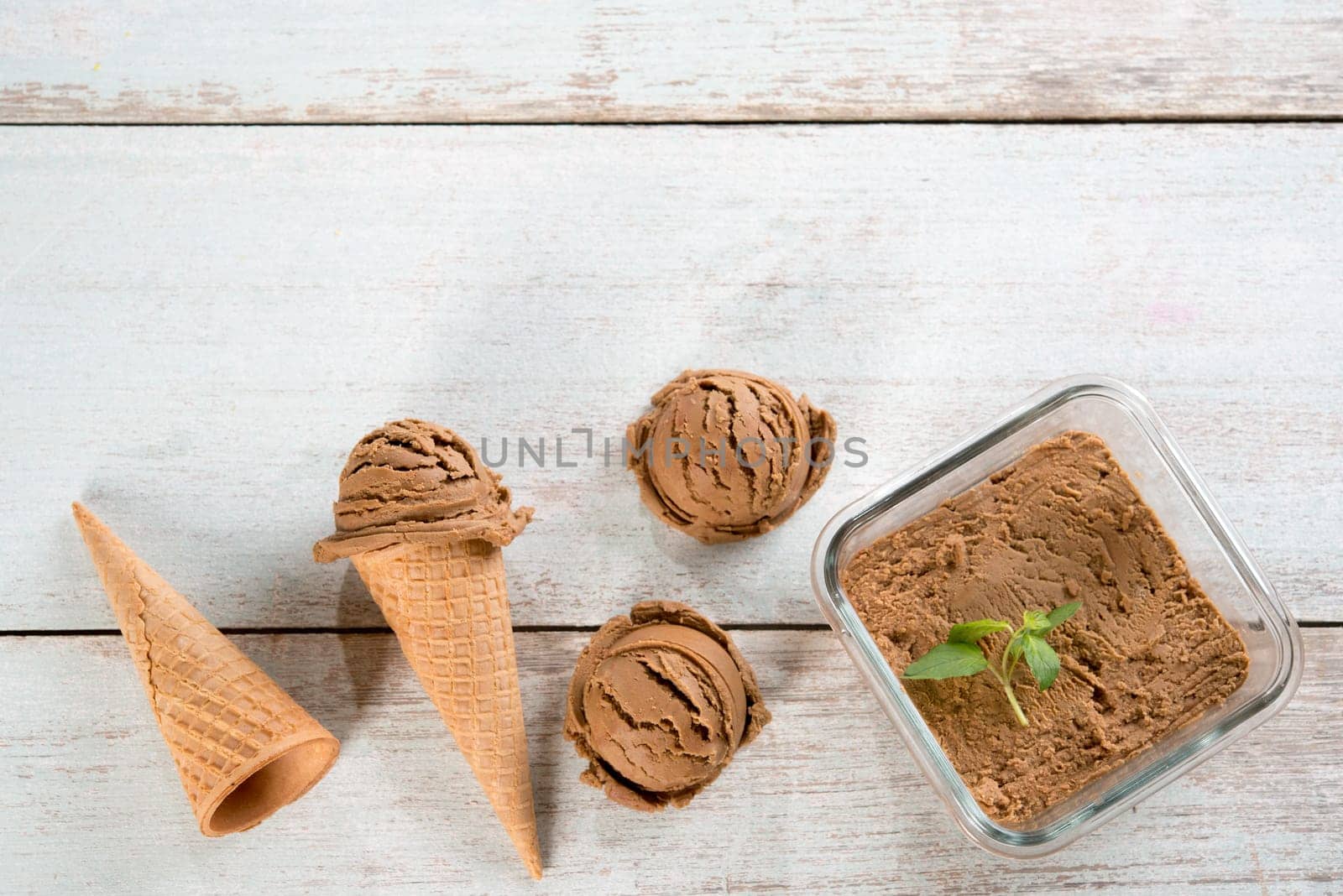 Top view chocolate ice cream in waffle cone on old rustic vintage wooden background. Copy space on above.