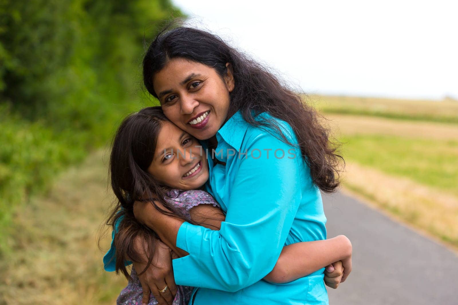 Mother hugs her daughter in summer
