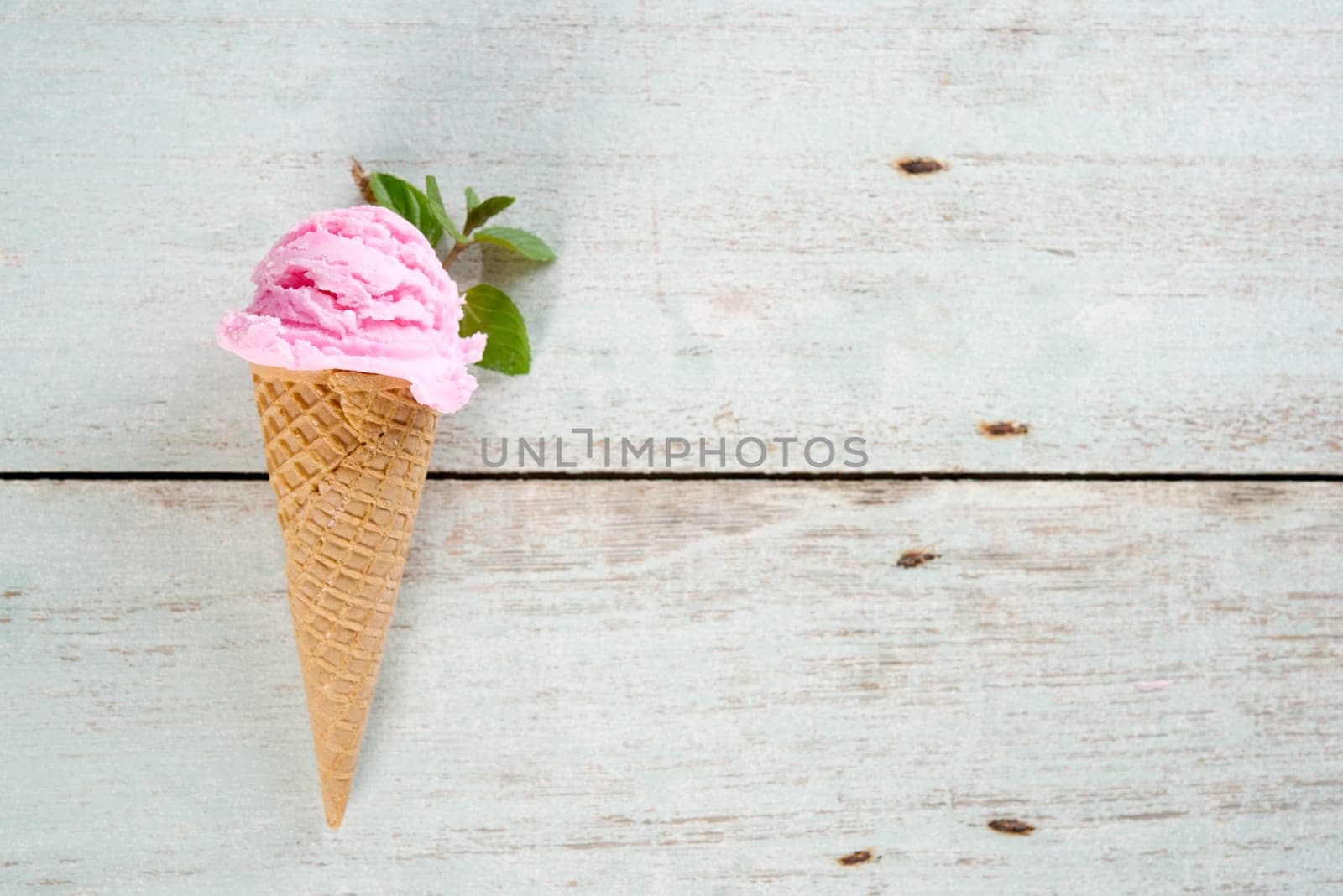 Top view strawberry ice cream waffle cone on wooden background, copy space on side.