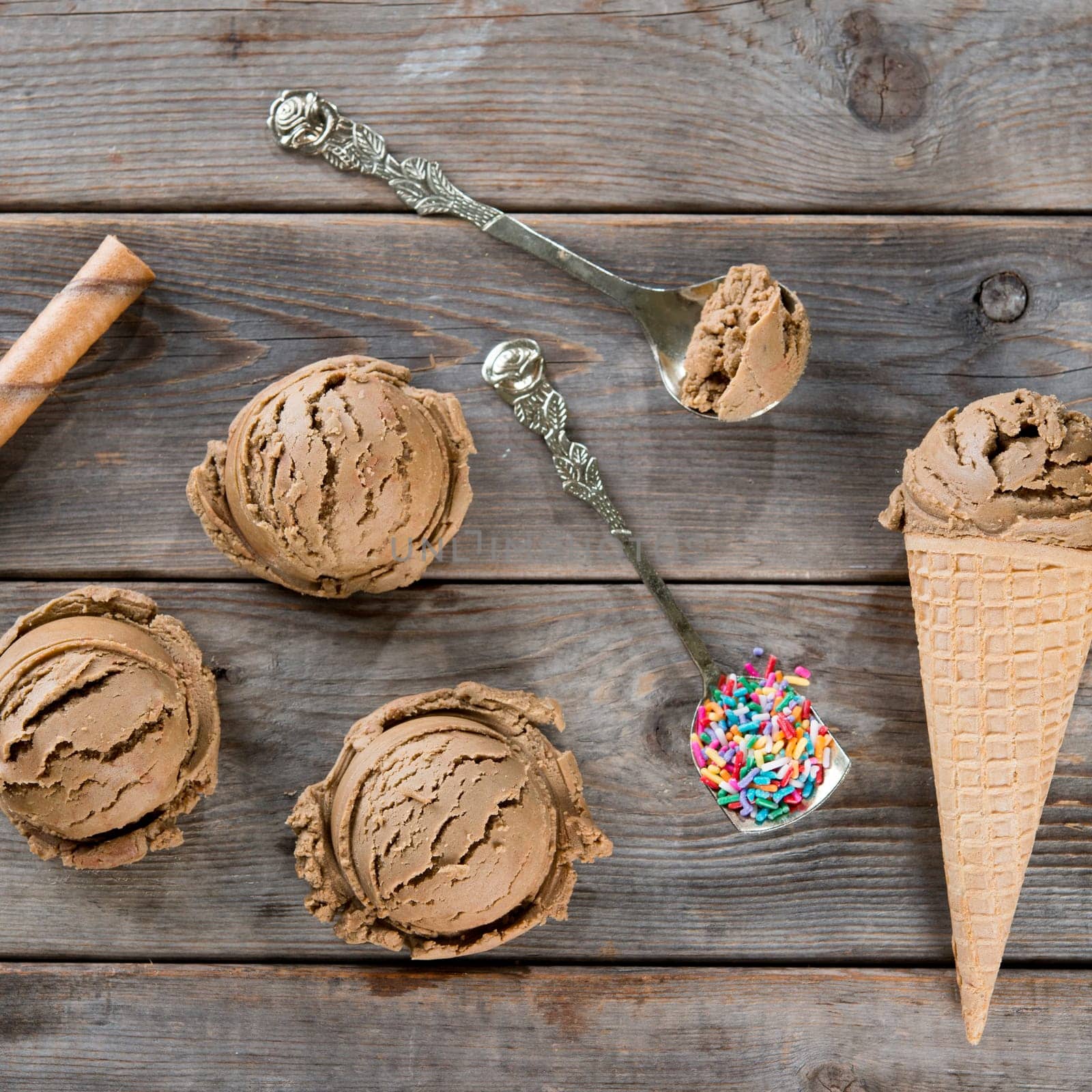 Top view chocolate ice cream in waffle cone on dark wooden background.