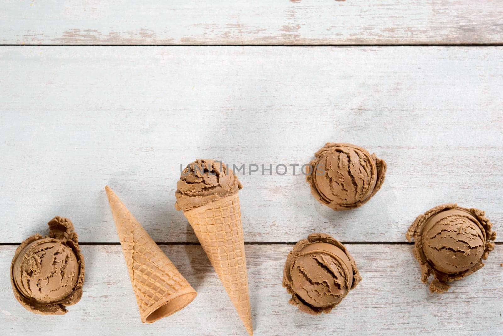 Top view chocolate ice cream in waffle cone on rustic vintage wooden background. Copy space on above.