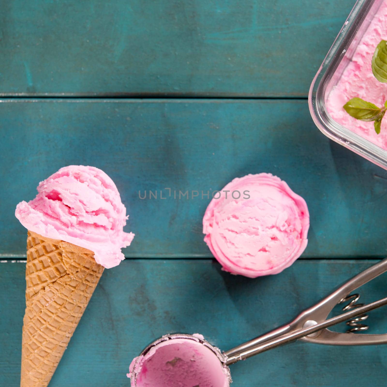 Top view pink ice cream waffle cone on blue wooden background