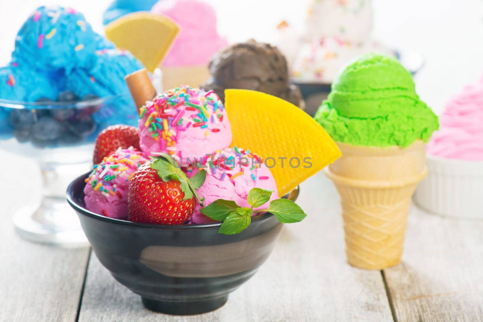 Different flavor ice cream in bowl on white rustic wooden background.