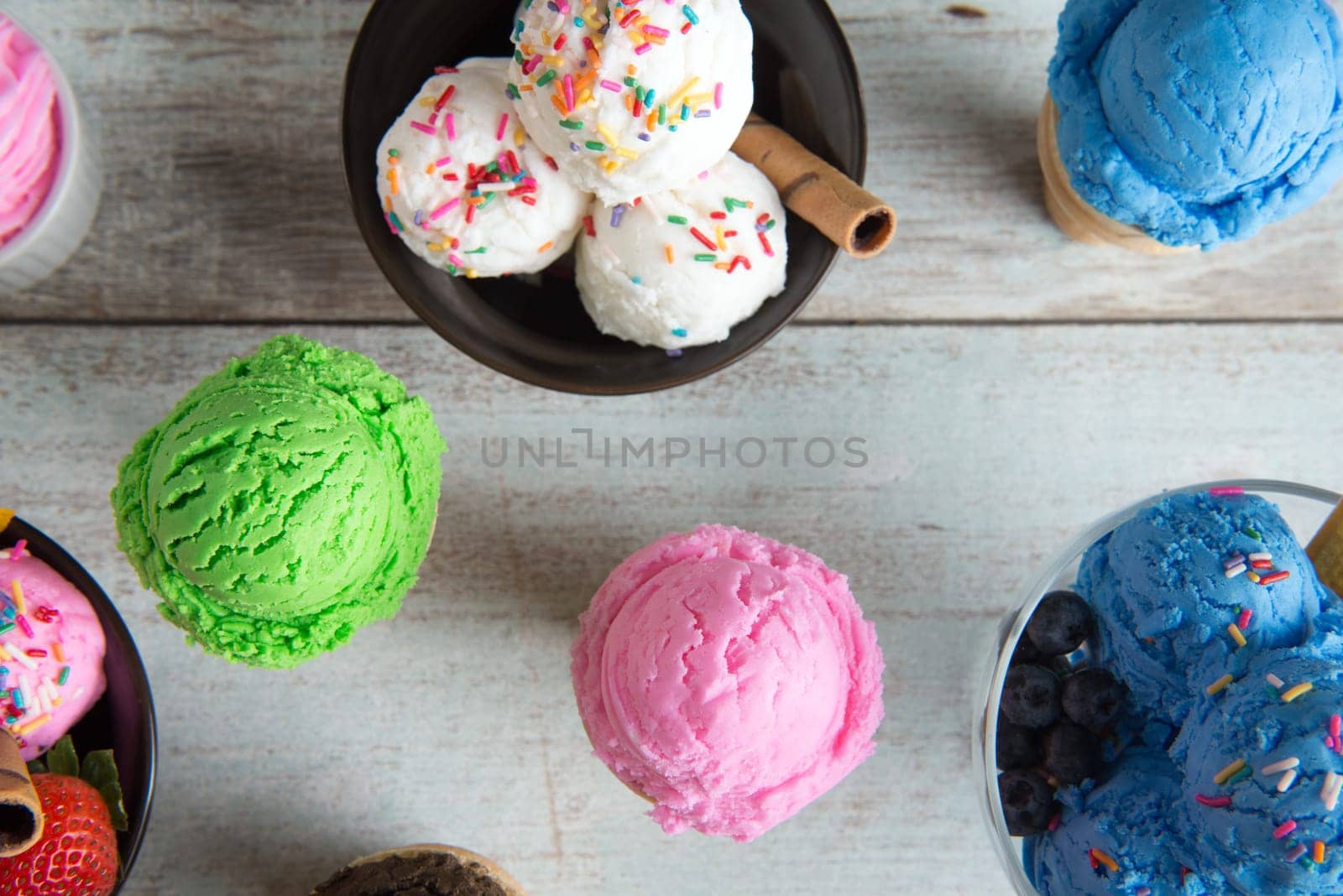 Top view different color ice cream in bowl on white rustic wooden background.