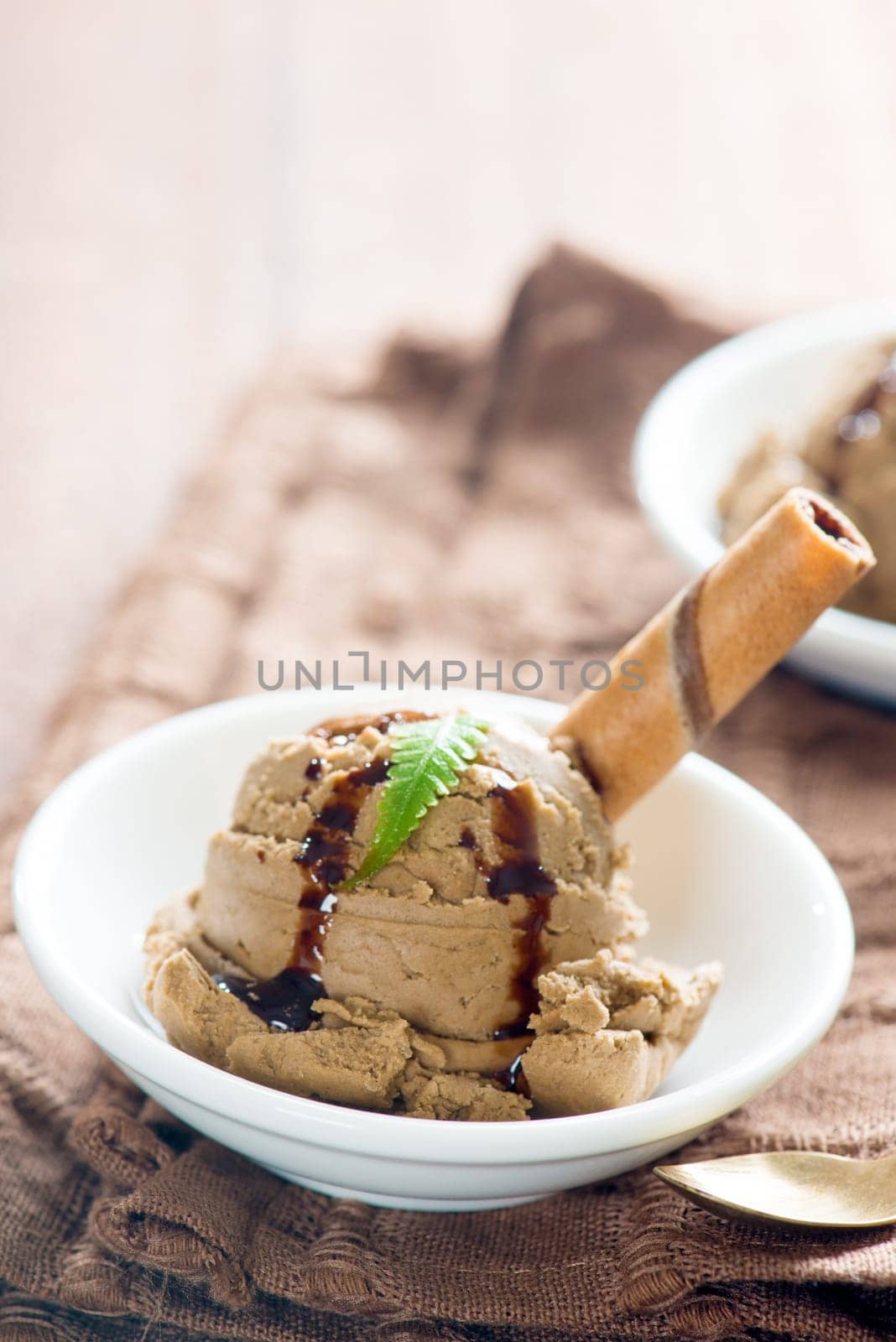 Close up plate of chocolate ice cream with syrup on dining table.
