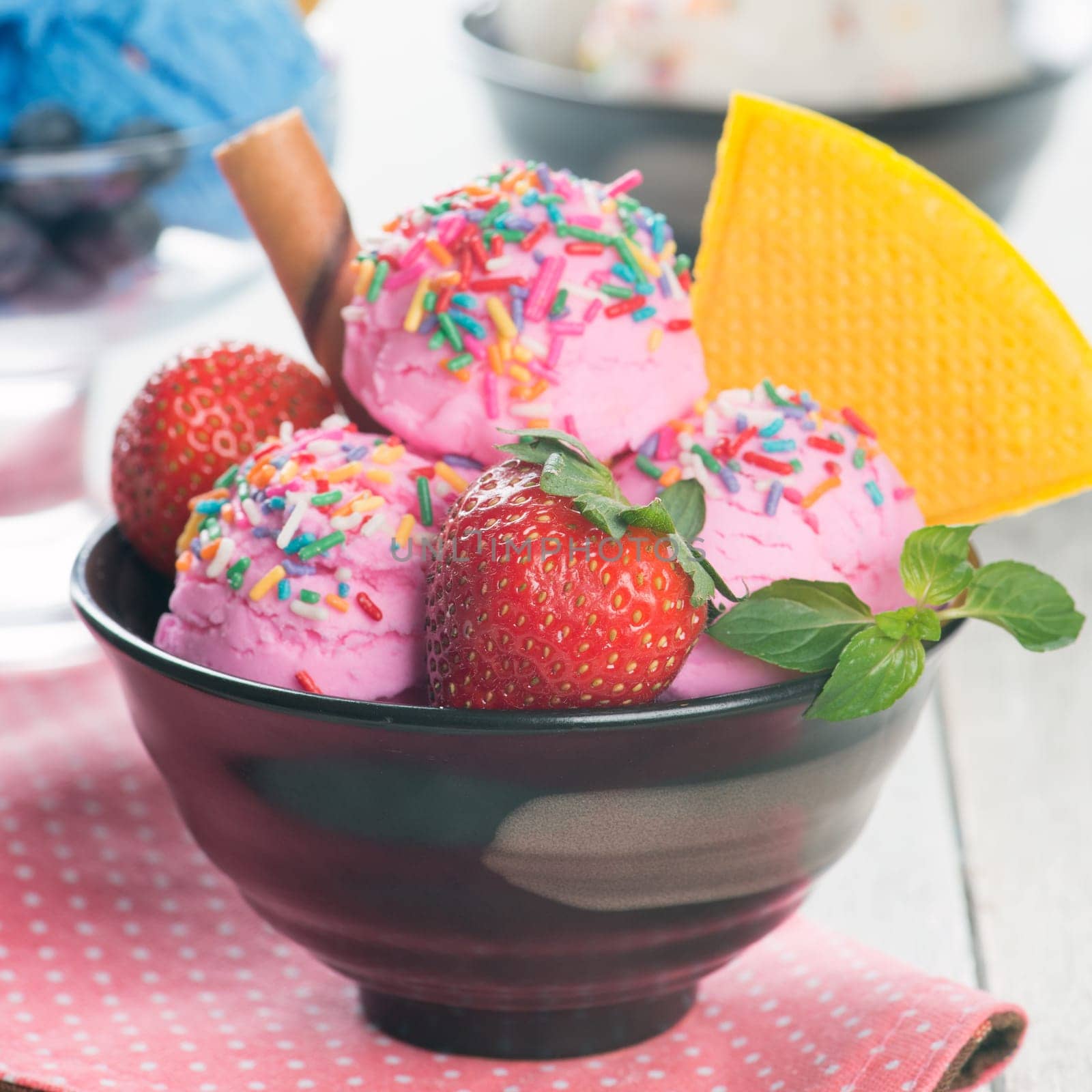 Pink ice cream in bowl with strawberry fruits and waffle