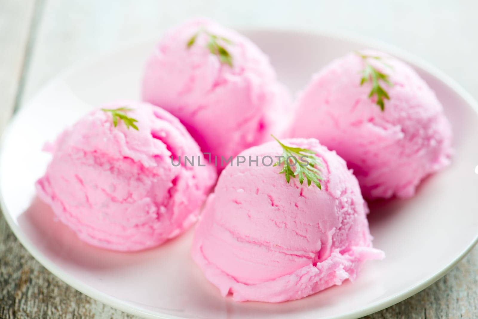 Strawberry ice cream plate on white wooden background.
