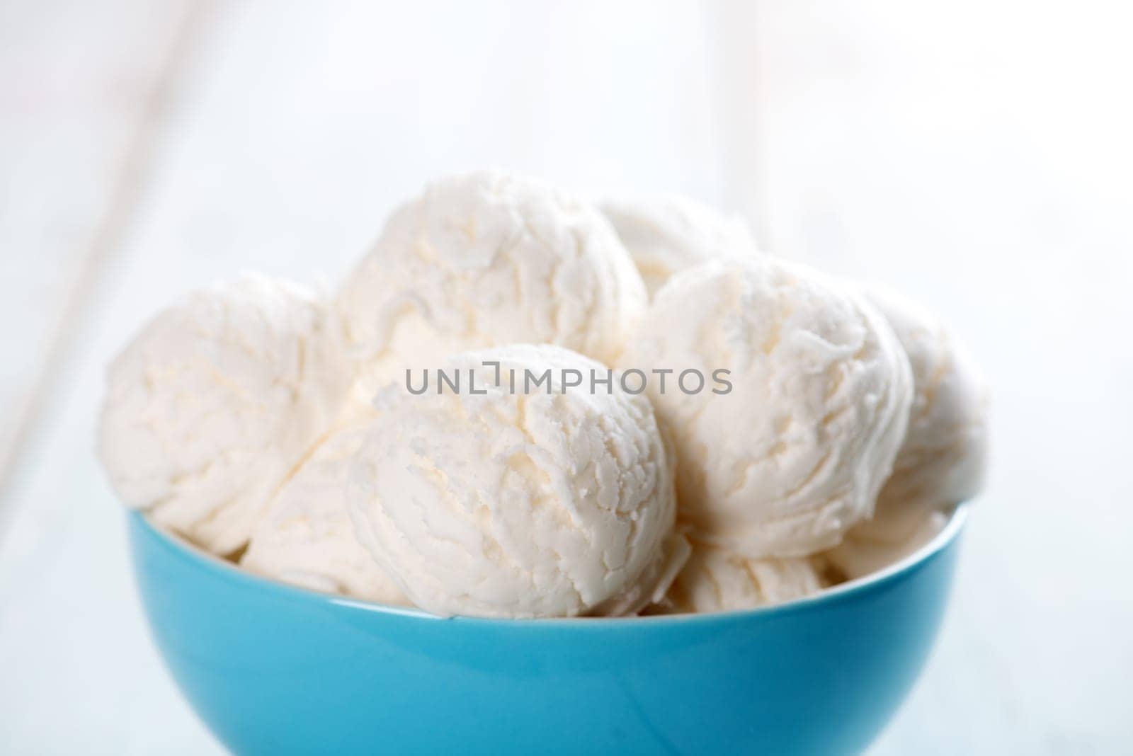 White ice cream in bowl on bright rustic wooden background.