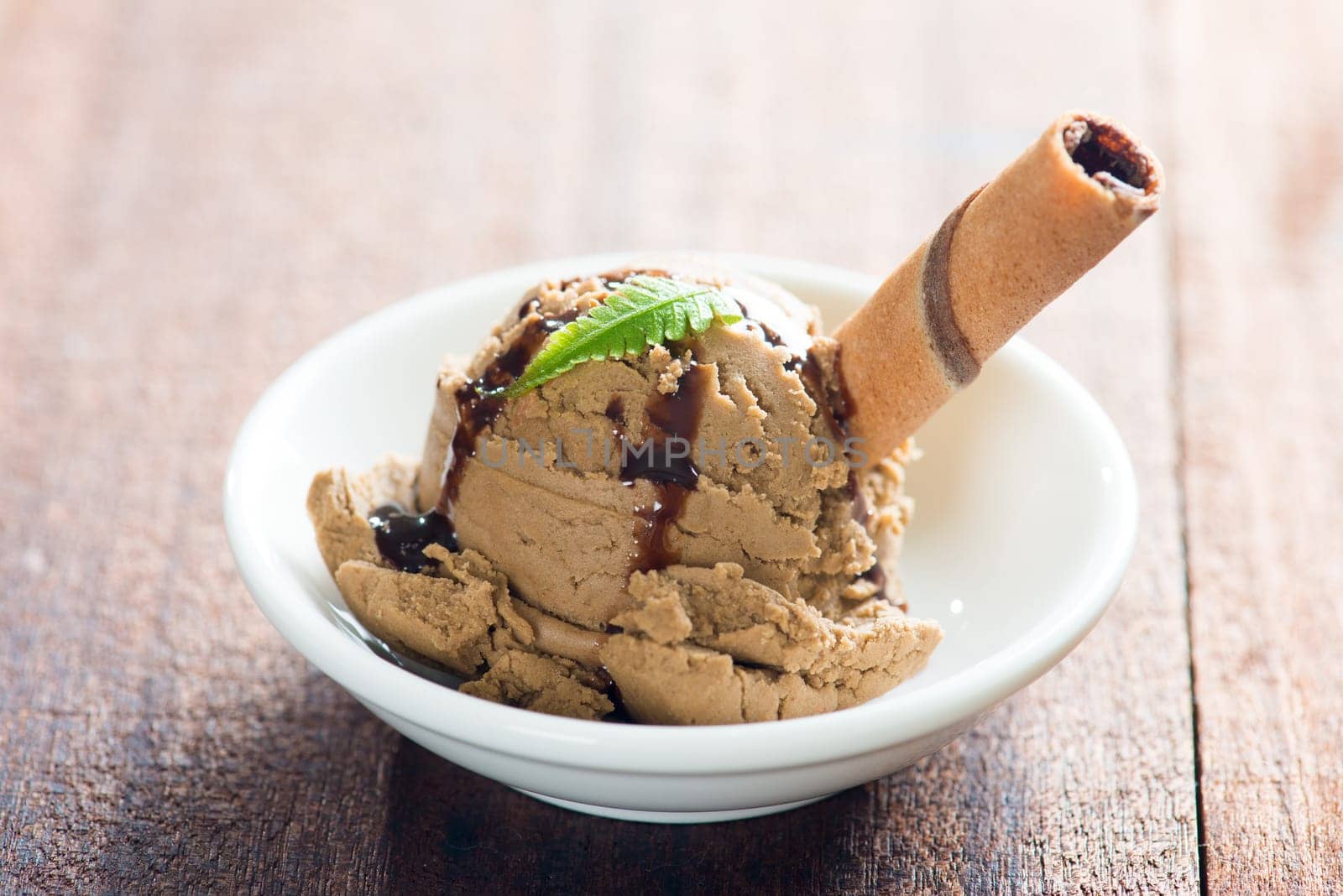 Plate of chocolate ice cream with syrup on dining table.