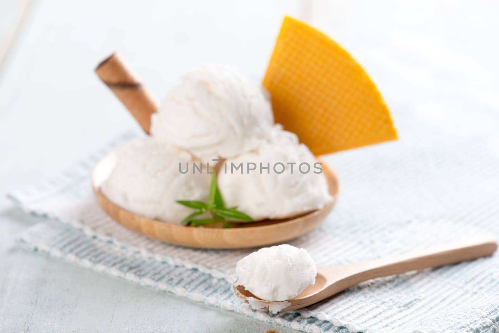 Vanilla ice cream in plate with waffle on white rustic wooden background.