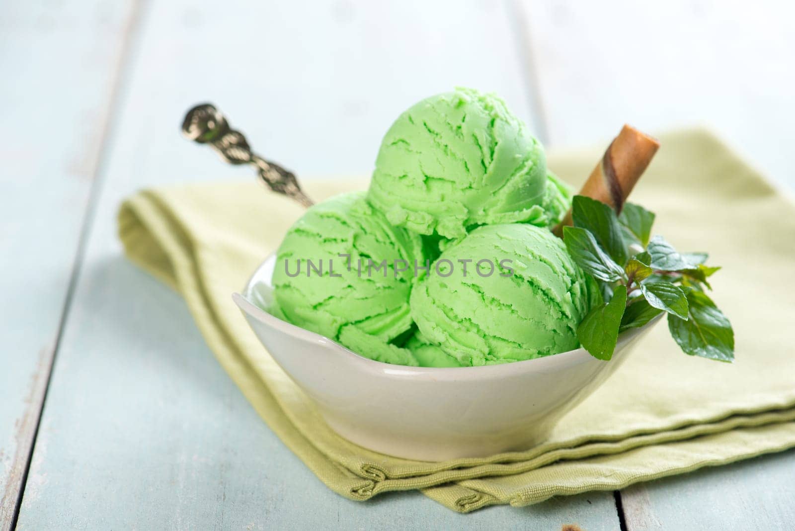 Scoop of mint ice cream in bowl on wooden background.