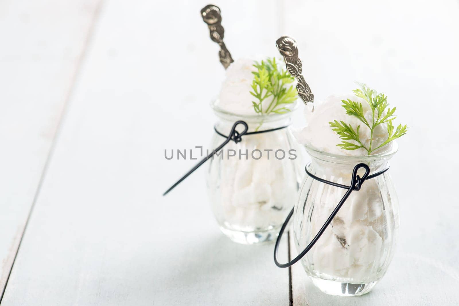 White ice cream in cup on bright rustic wooden background.