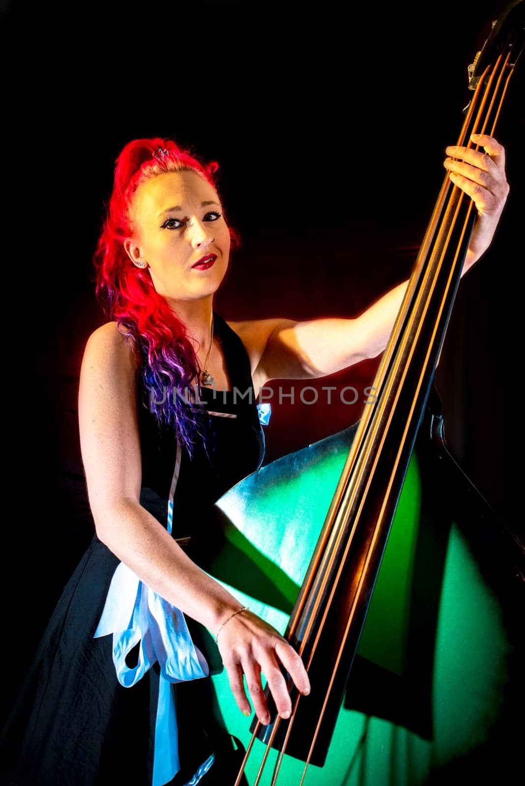 Rock'n'Roll singer with red hair and double bass against a dark background