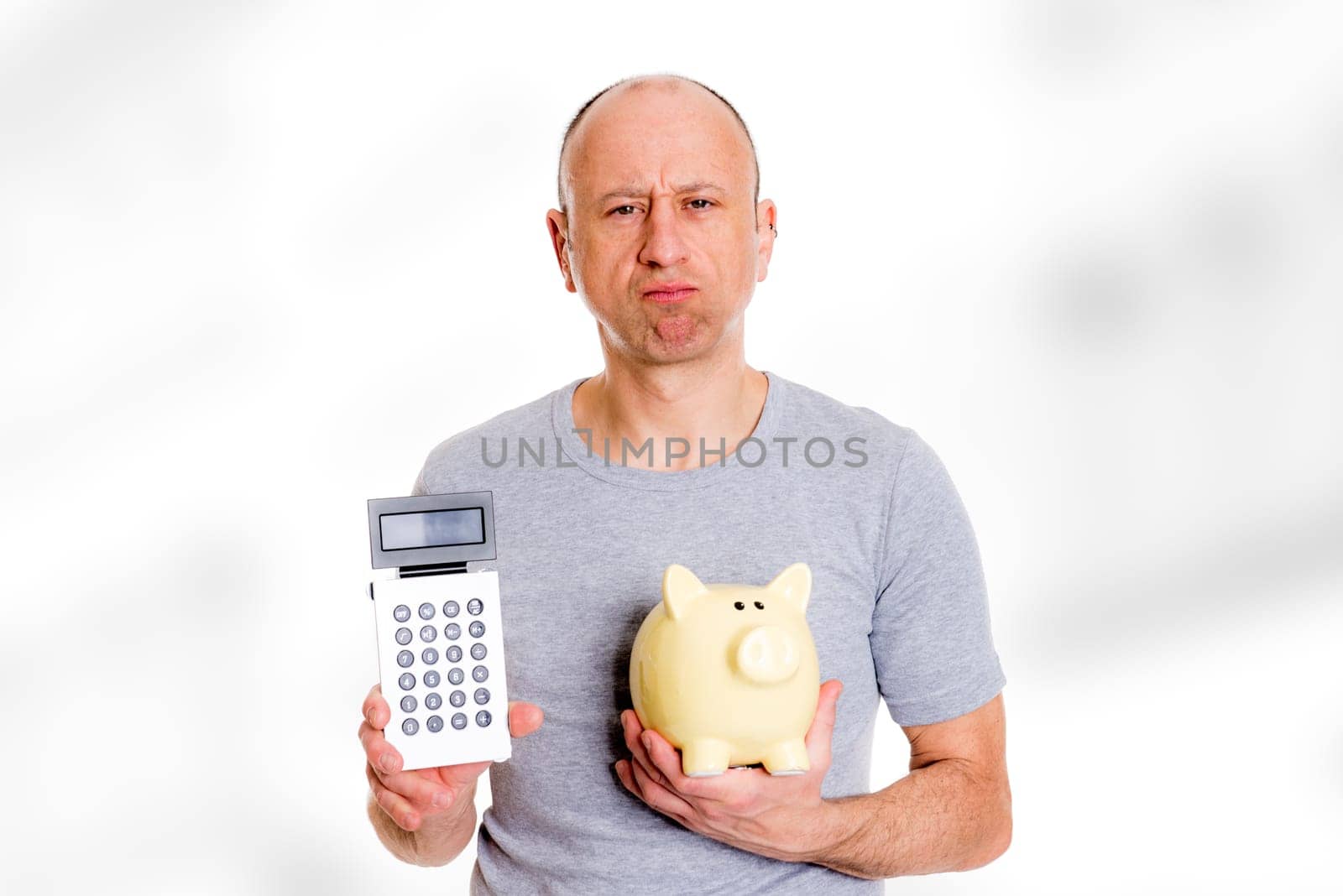 young man in gray shirt with pocket calculator and piggybank