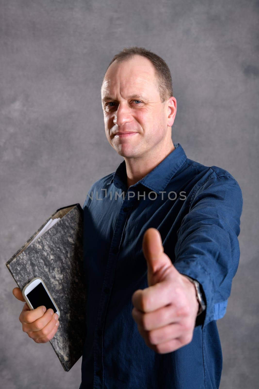 young businessman with folder, phone and thumb up