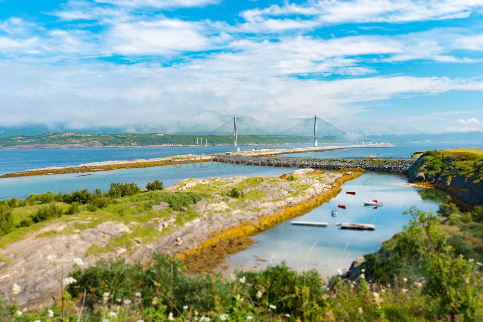 Panorama of bridge and car road in Norway, Europe. Auto travel through scandinavia. Blue cloudy sky, lake and bridge in background.