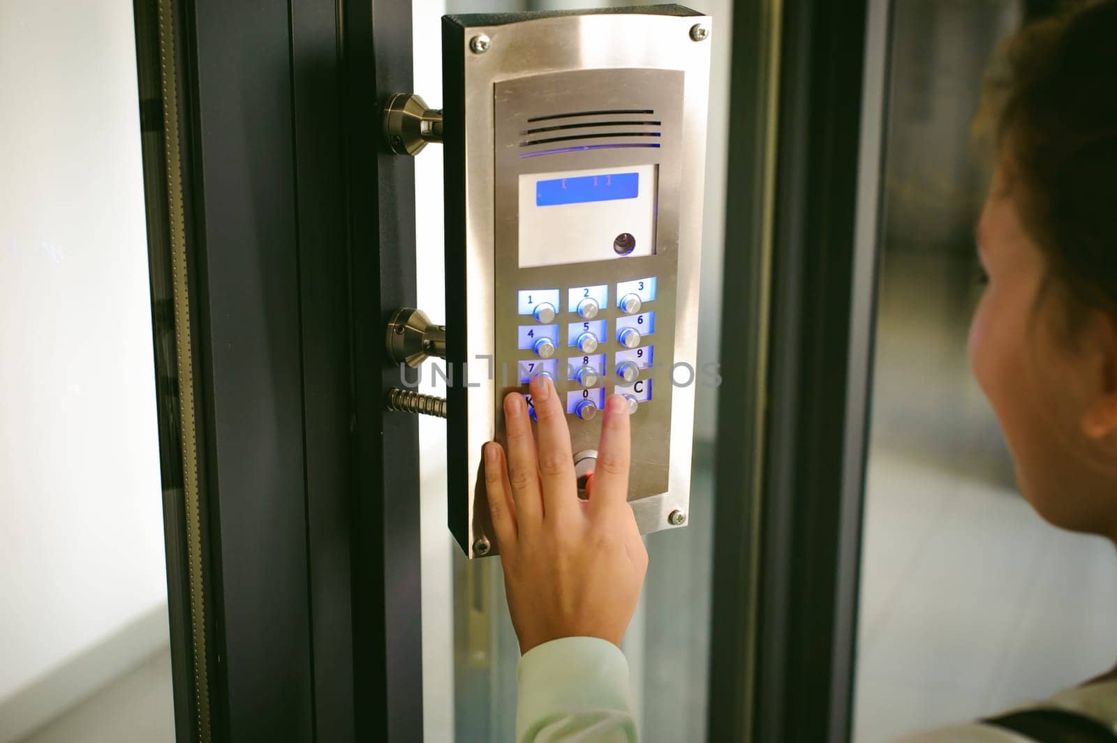 young blond teenager schoolgirl dials the code for a call over the intercom