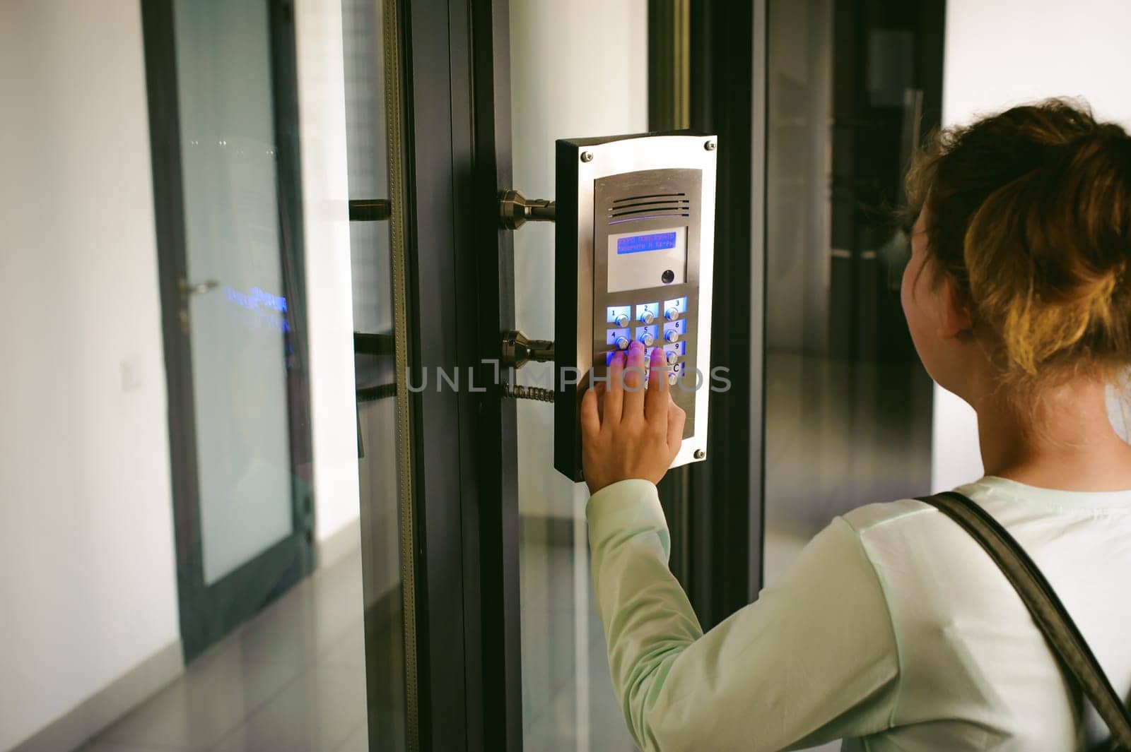 young blond teenager schoolgirl dials the code for a call over the intercom