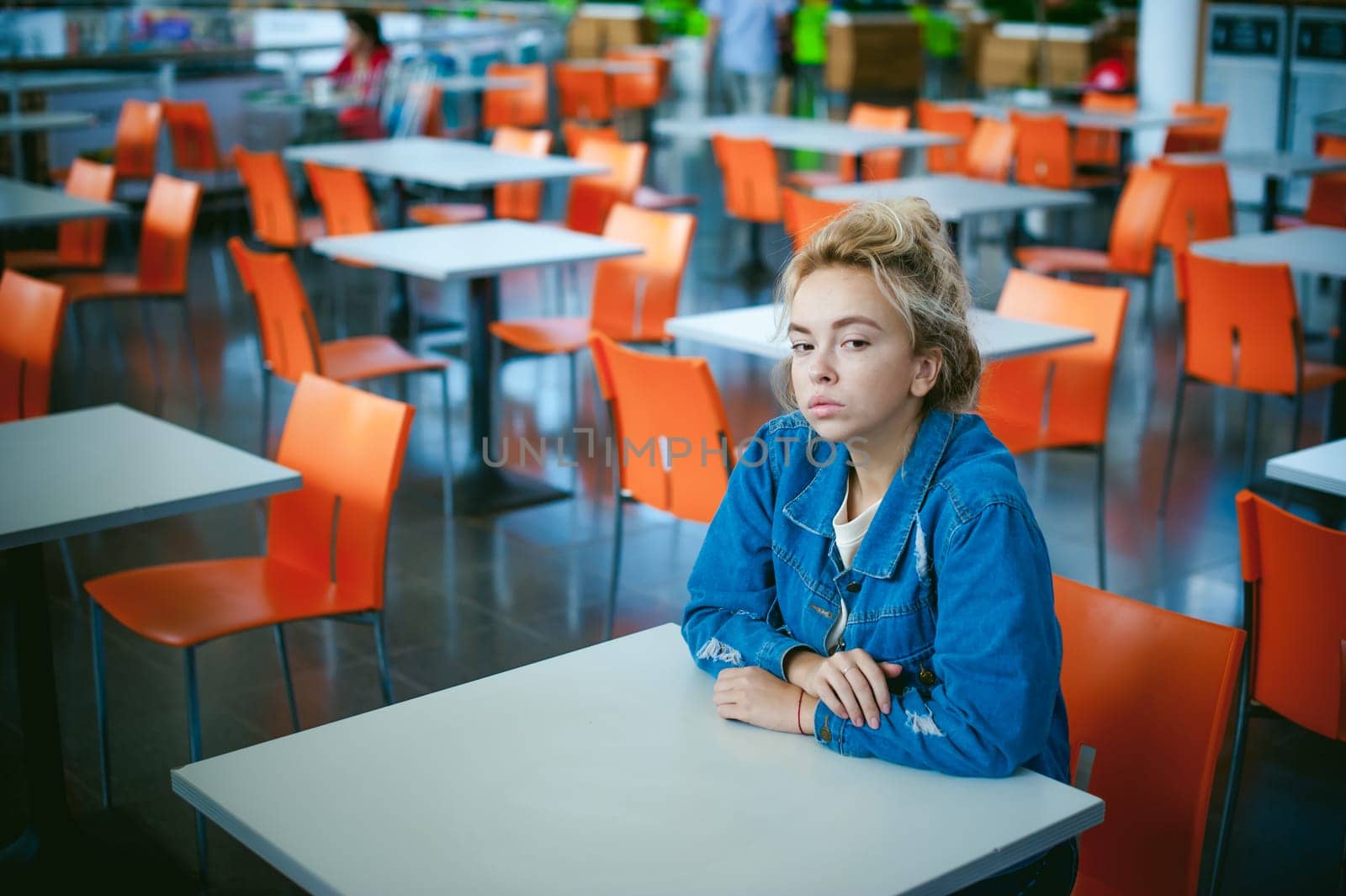 young beautiful woman in jeans clothes in business space of shopping center. portrait of a girl with freckles on her face, stylish girl in an empty cafe