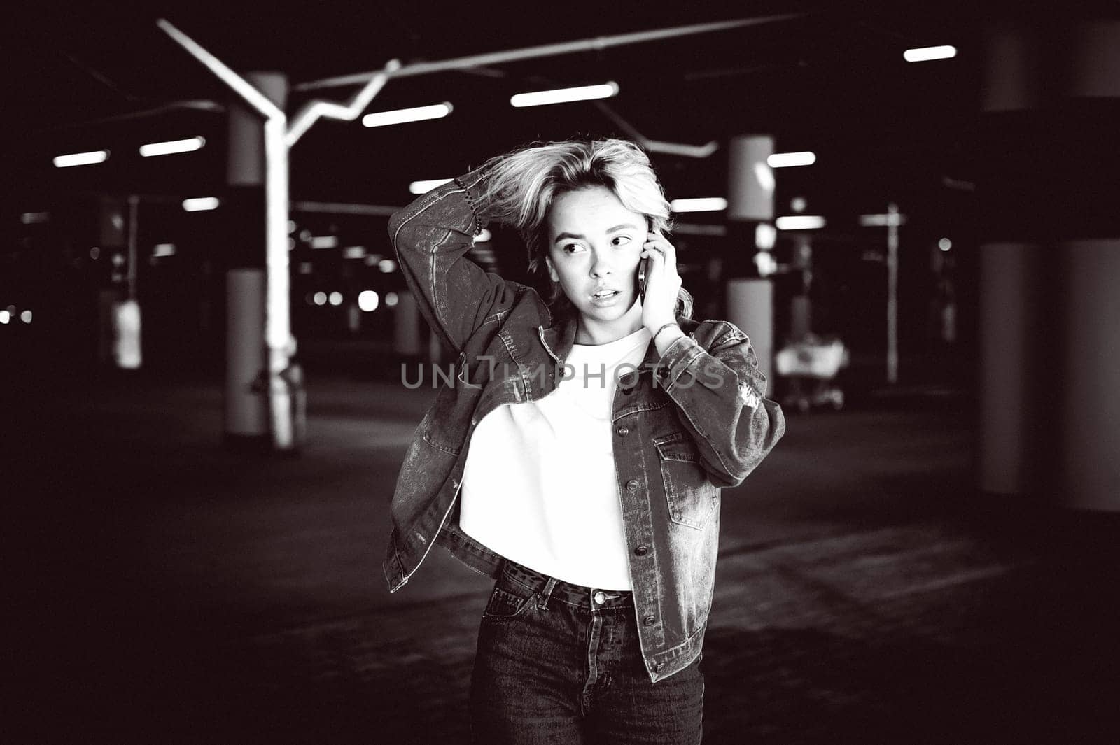young beautiful woman in jeans clothes in parking of shopping center. portrait of a girl with freckles on her face, stylish girl standing with a cell phone