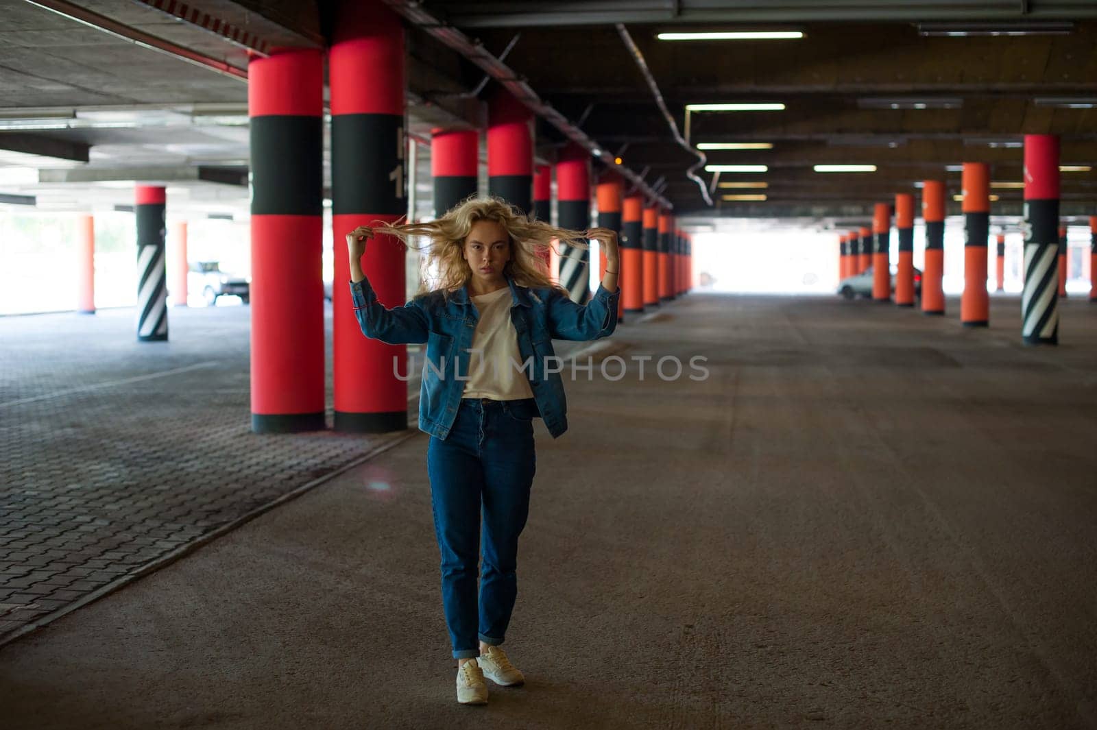young beautiful woman in jeans clothes in parking of shopping center. portrait of a girl with freckles on her face