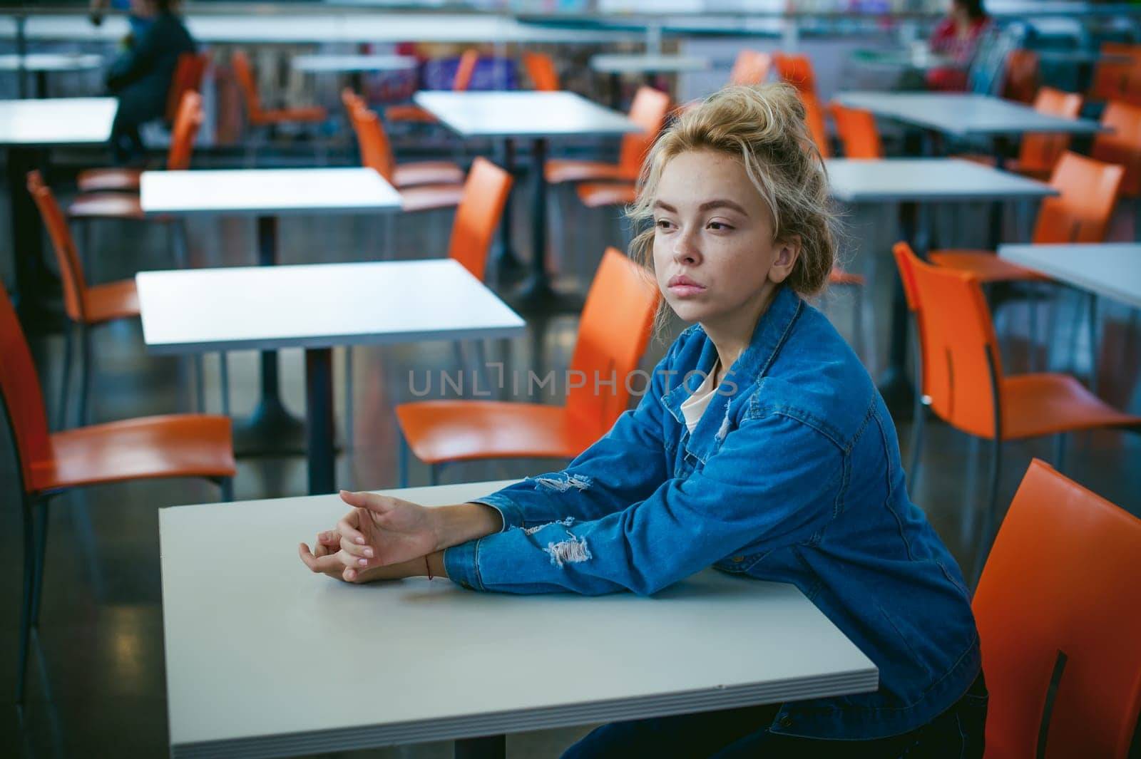 young beautiful woman in jeans clothes in business space of shopping center. portrait of a girl with freckles on her face, stylish girl in an empty cafe