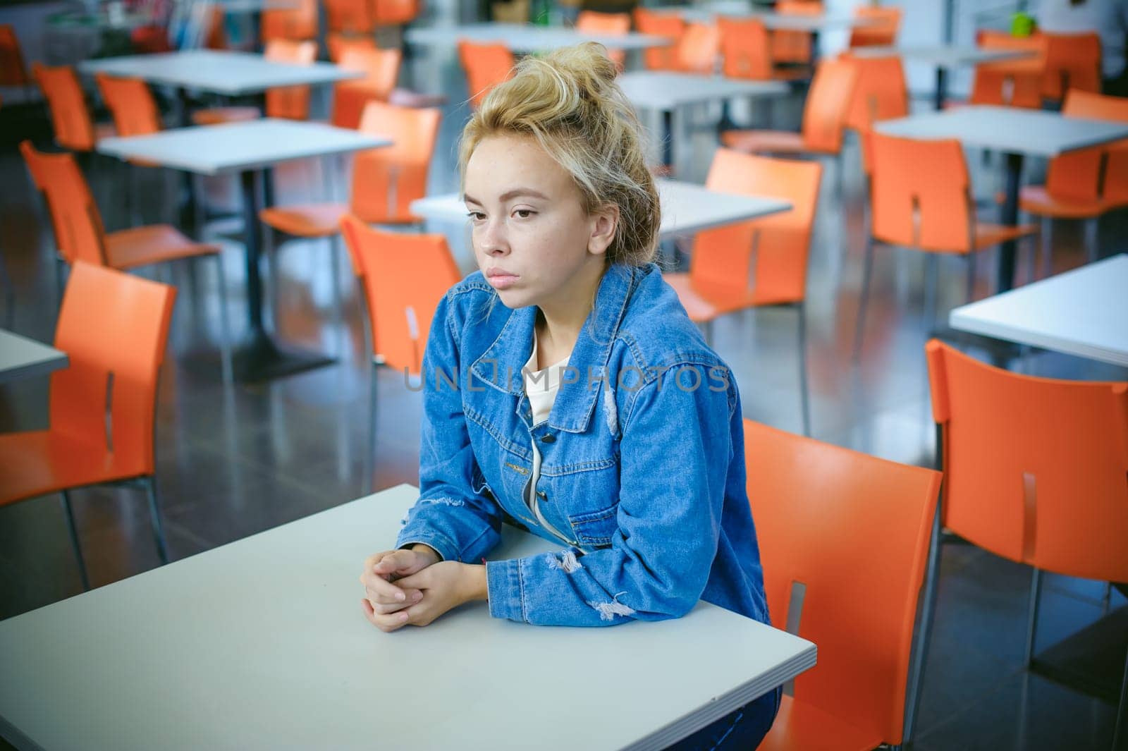 young beautiful woman in jeans clothes in business space of shopping center. portrait of a girl with freckles on her face, stylish girl in an empty cafe